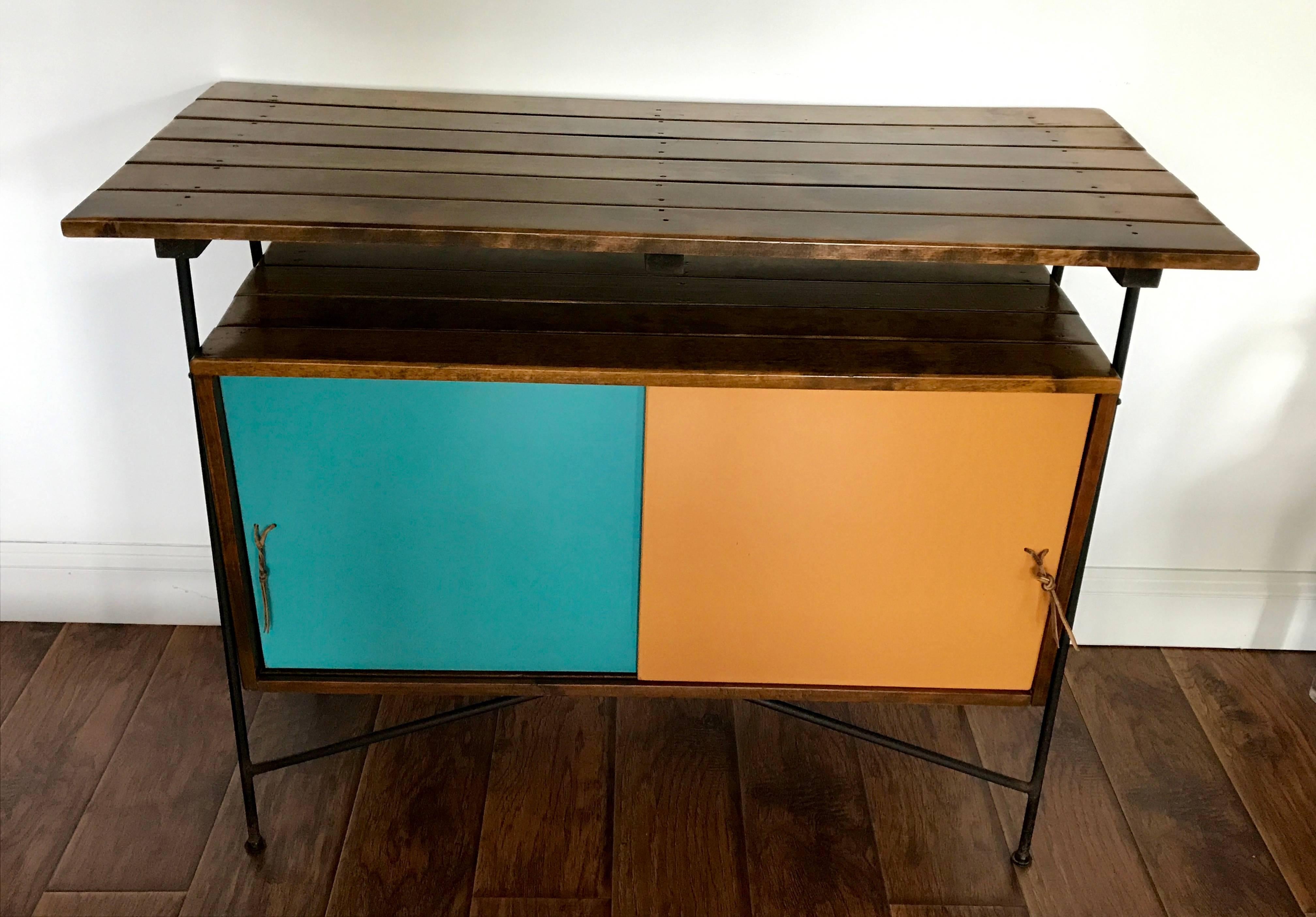 Very cool piece by Arthur Umanoff, can be used as a bar, sideboard, foyer table or server. Umanoff's signature style consisting of slat wood, wrought iron and laminate. Leather pulls for sliding doors. Back is finished in white laminate. All