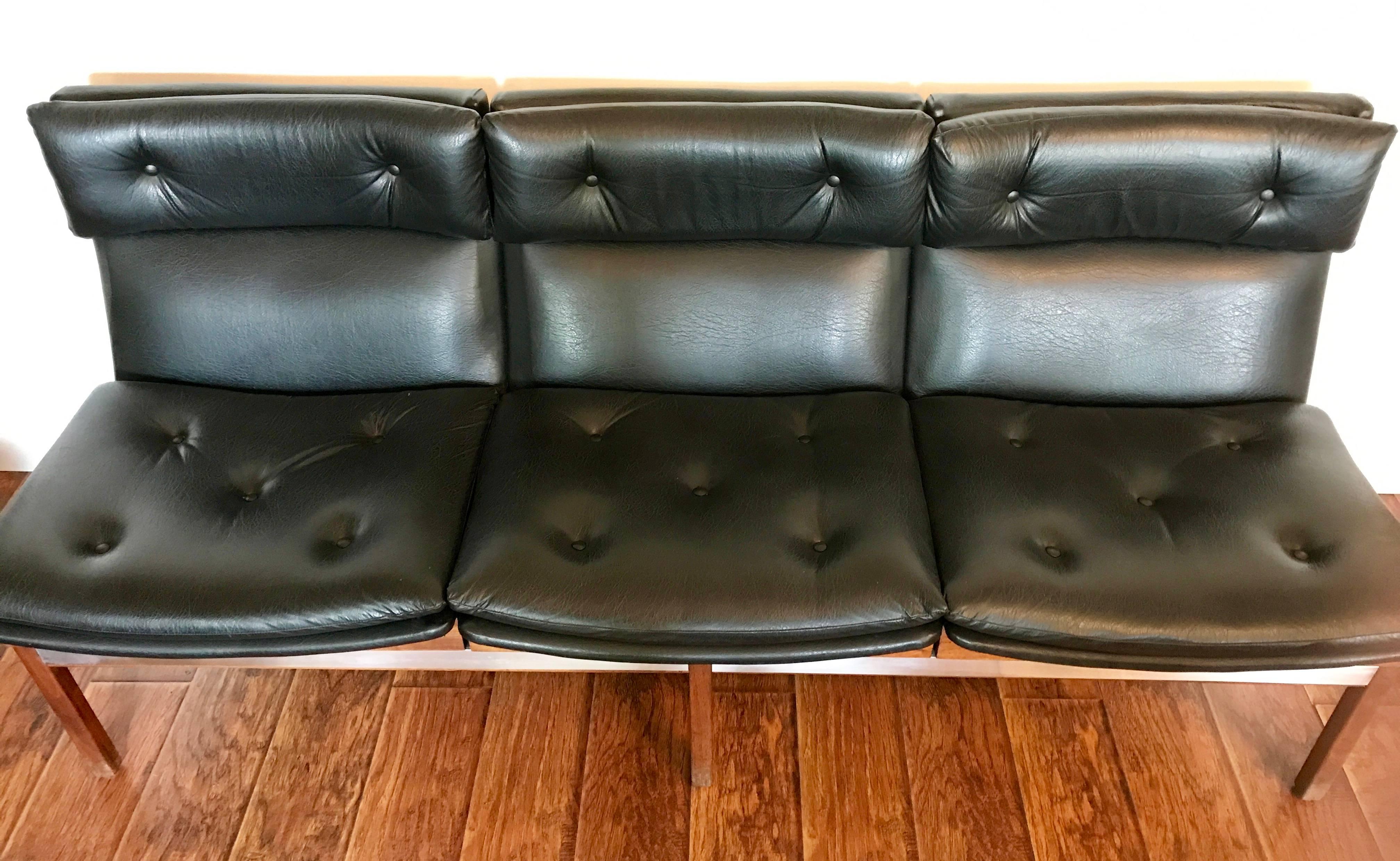 Very cool Arthur Umanoff sofa manufactured by Madison Furniture Co. Three seats mounted on a walnut frame with aluminium accent strips. Black vinyl is in very good condition with no rips. Legs have wear appropriate with age and use. Please see