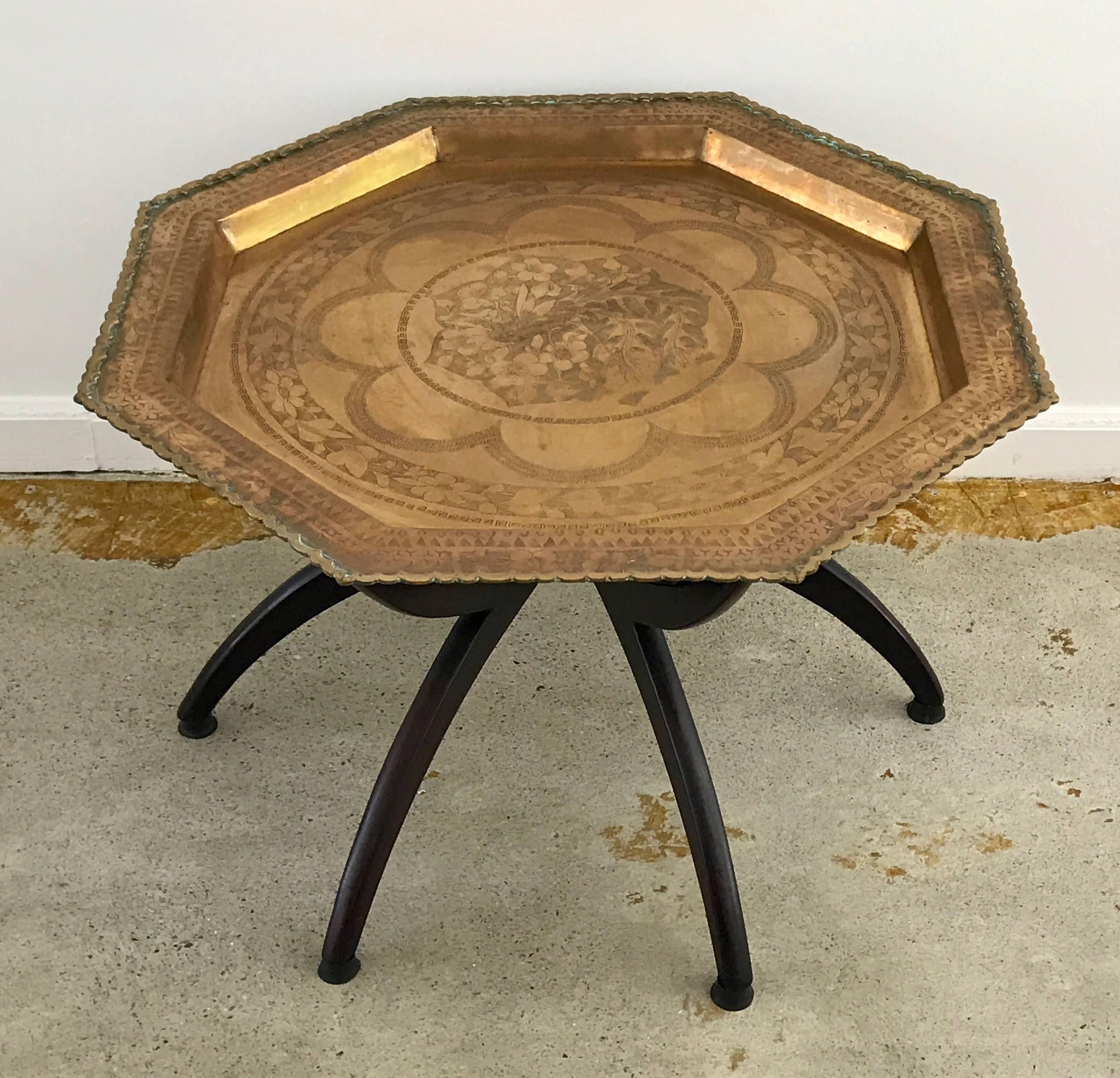 Beautifully detailed brass top tray table that rests on spider leg stand, circa 1950s. The octagon shaped tray is hand-etched and very intricate in detail. This piece was made in Hong Kong, unlike the mass produced trays from India and Morocco.