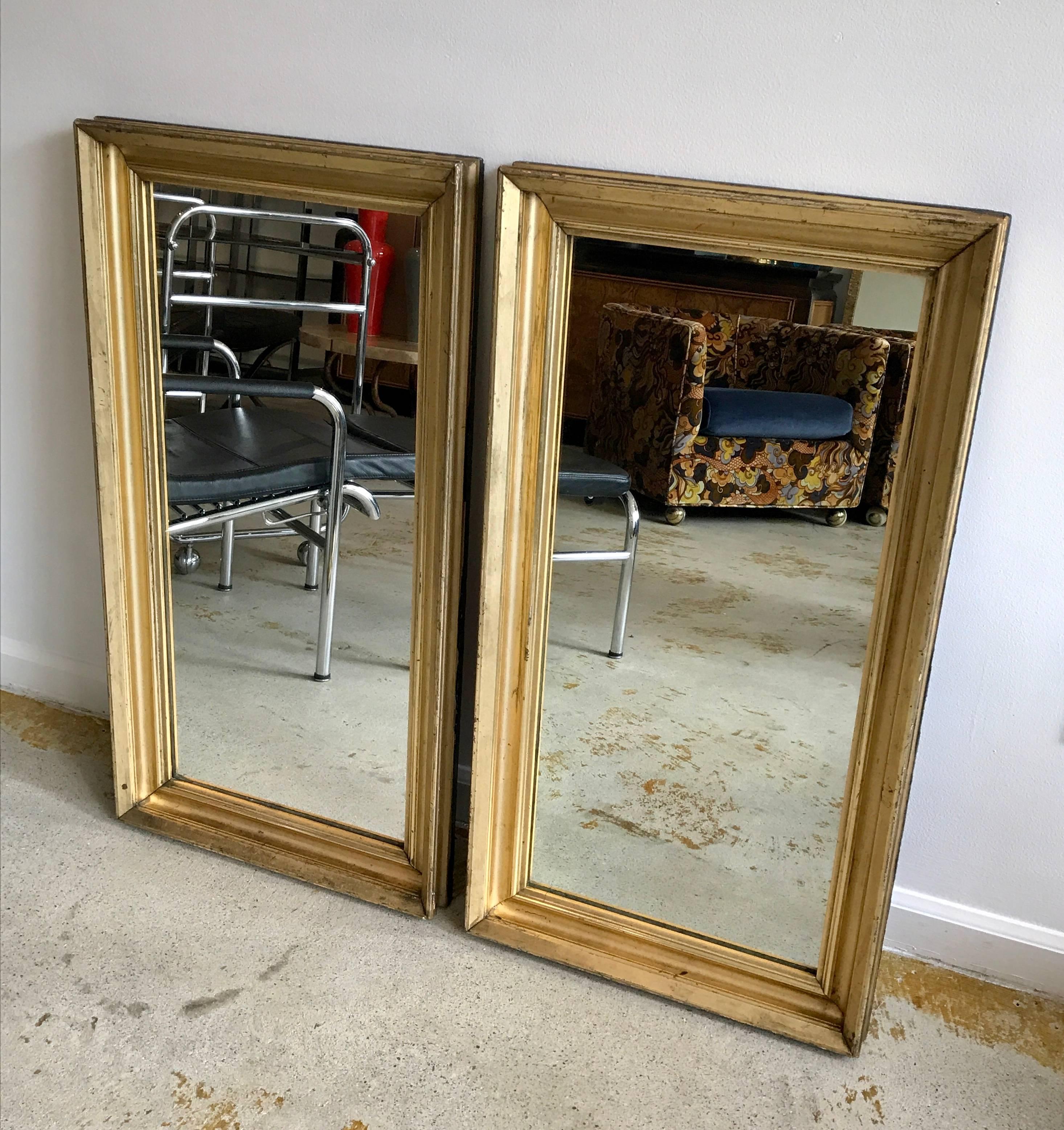 Very chic pair of gold gilt mirrors with original finish and aged patina. Classic clean lines.
