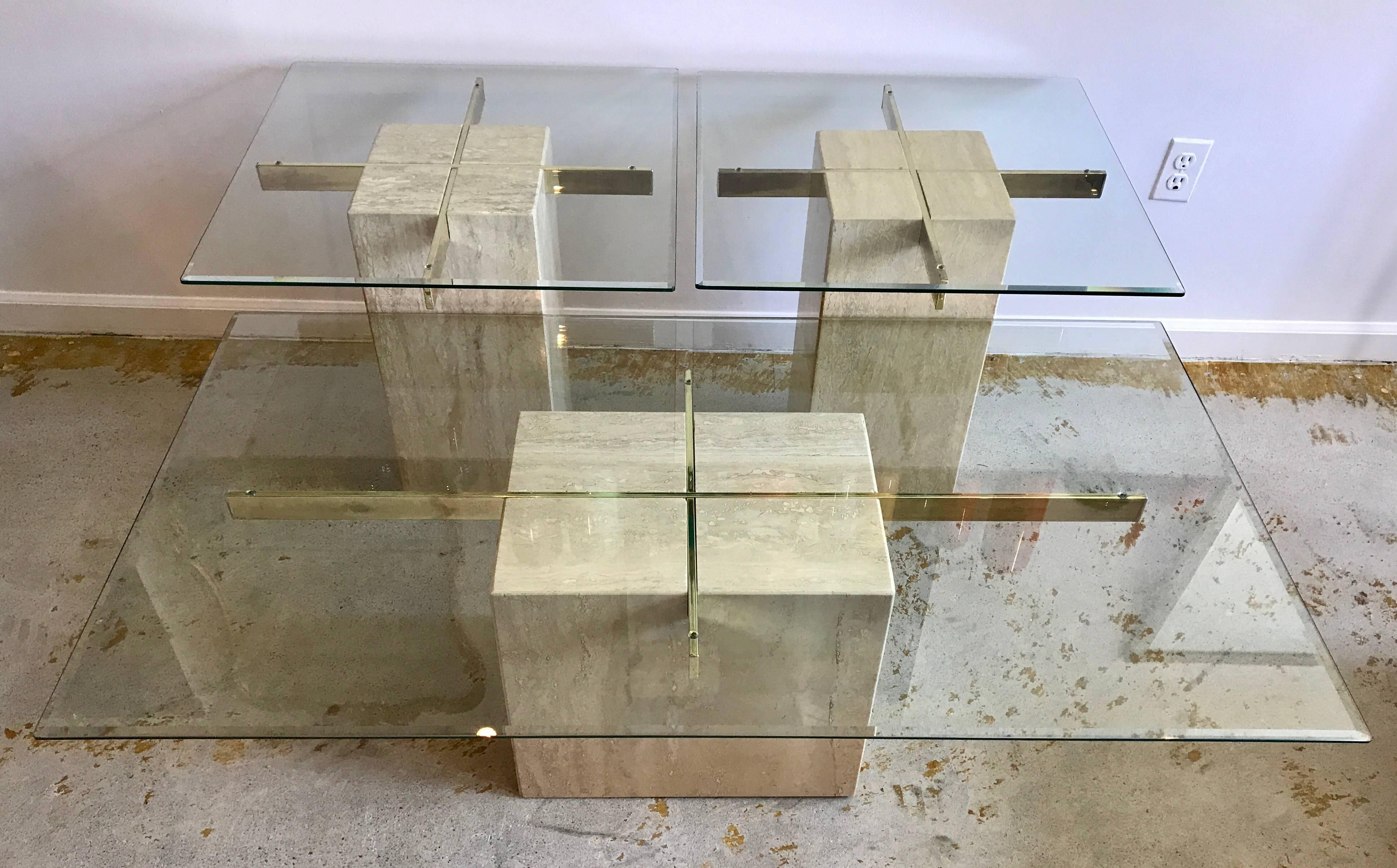 This iconic Italian-made coffee table and side tables designed by Artedi of the United Kingdom, has beveled glass panels sitting on polished brass cross which is embedded in the travertine cubes. The set is in good vintage condition with slight