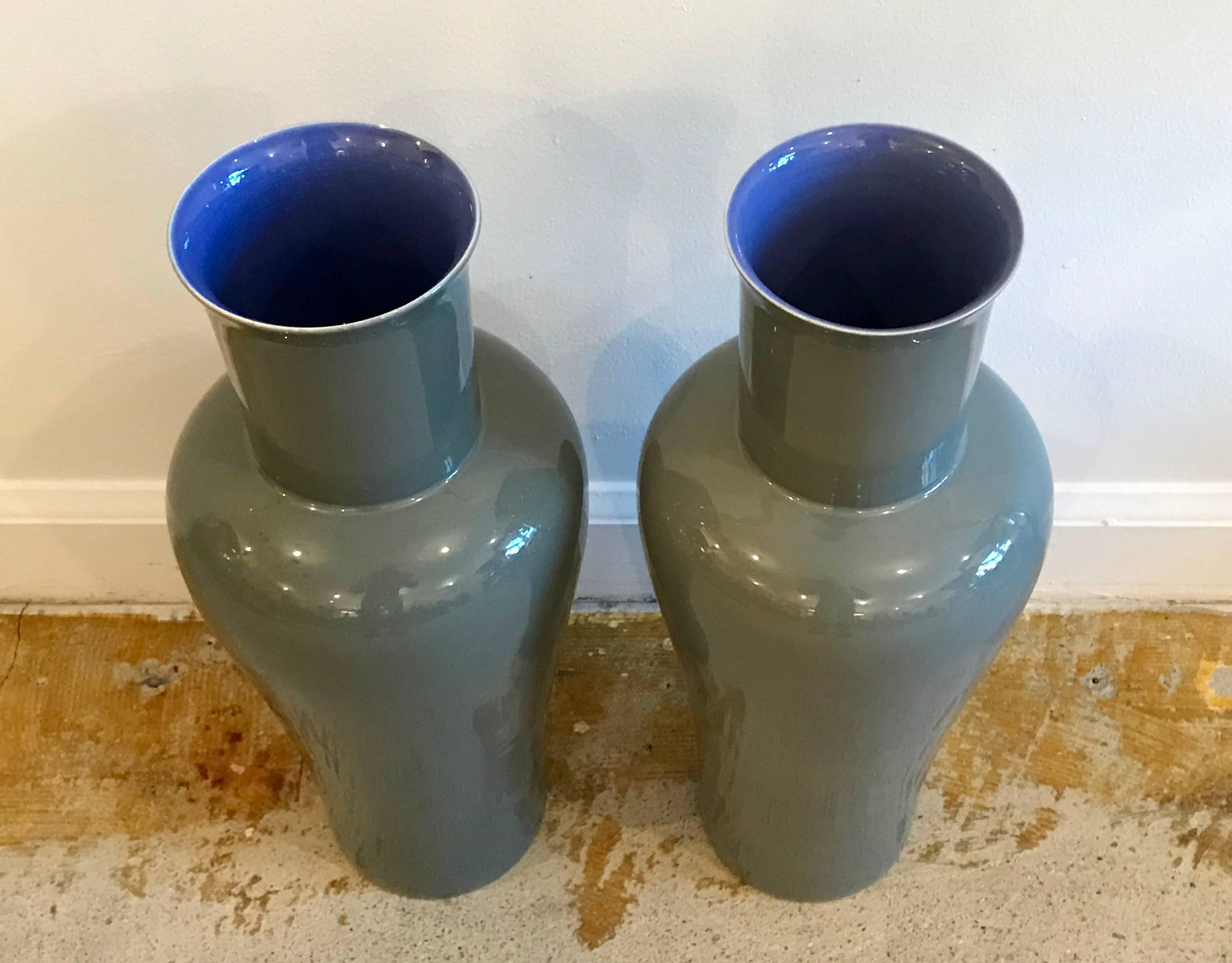 Beautiful pair of contemporary handcrafted porcelain vases by Artist Bo Jai for Middle Kingdom. Putty Gray with contrasting vibrant blue interior. The vases are kiln fired in Jingdezhen China. Each piece signed by the artist.