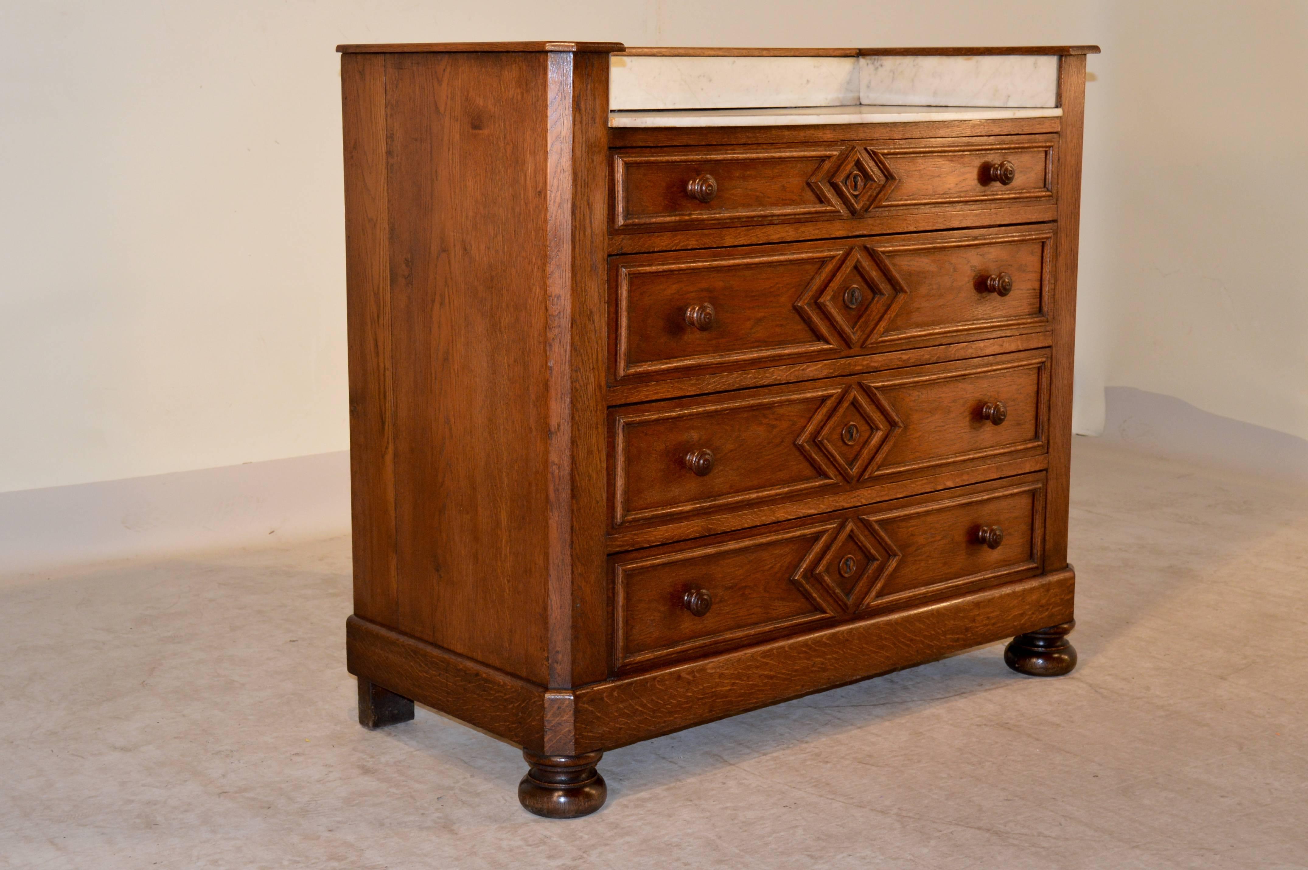 19th century French wash stand made from oak with marble top and backsplash, simple sides, and four drawers with lovely applied molded drawer fronts in a geometric pattern. Raised on bun feet. Counter height is 32.38.
