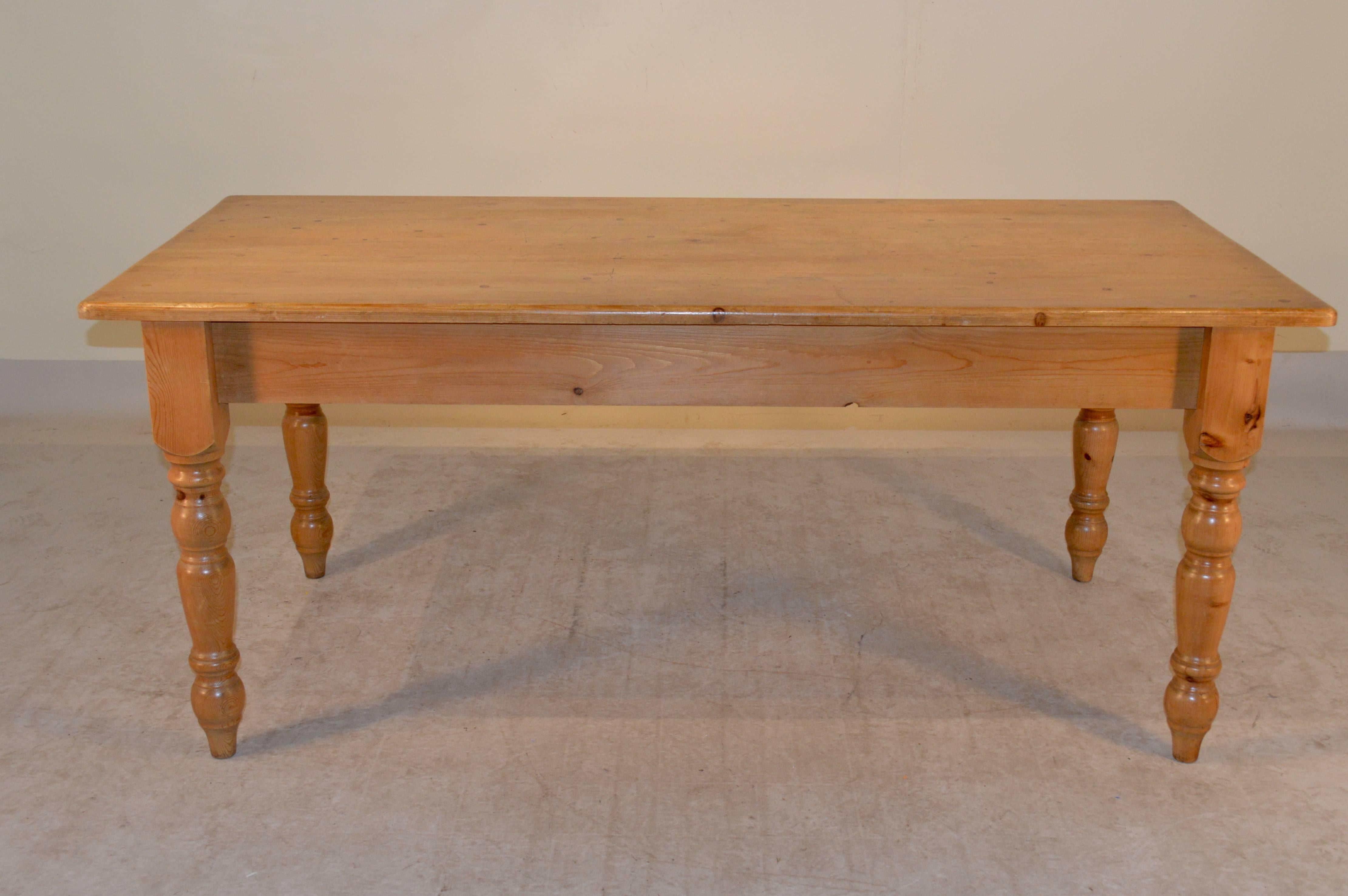 English farm table made from pine with a plank top following down to a simple apron and raised on lovely hand-turned legs, circa 1950. The apron measures 23.5
