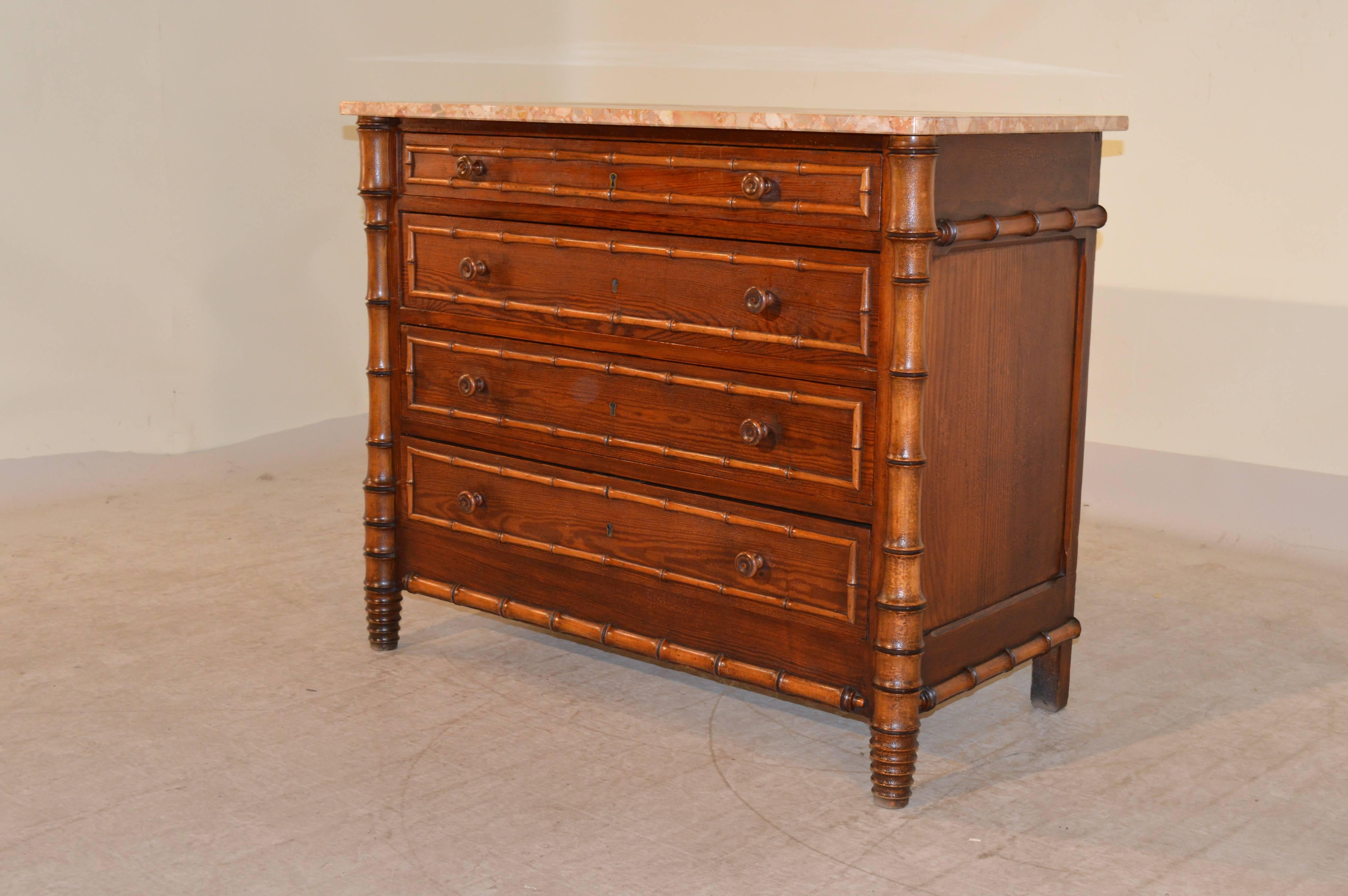 19th century French chest of drawers made from pine with a gorgeous color marble top, following down to four graduated drawers with faux bamboo turned molding, flanked by two hand-turned columns, in matching bamboo style. The sides are also paneled.