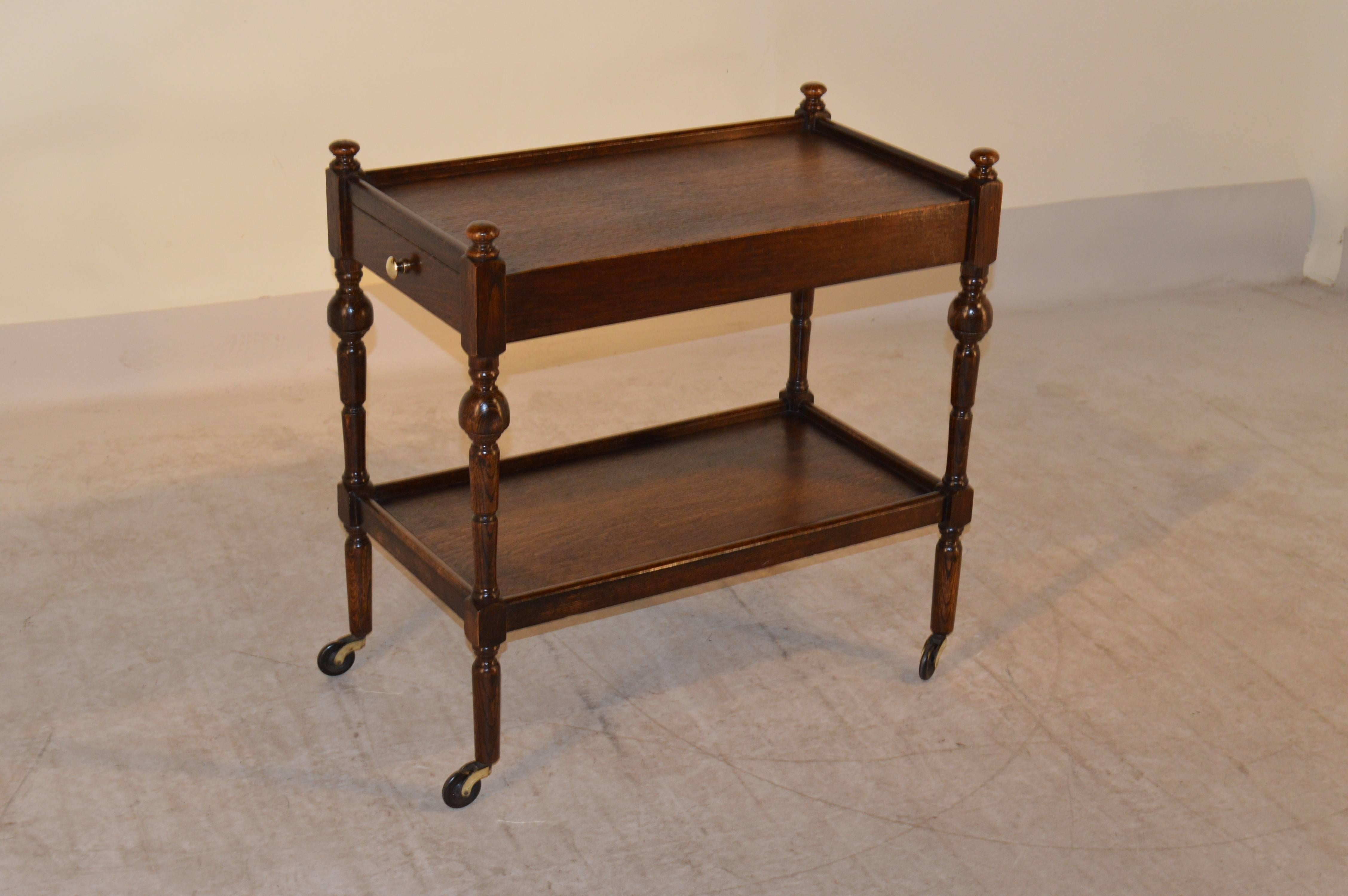 English oak drinks cart, circa 1900 with two shelves and a single drawer, raised on hand-turned legs which end in the original casters.