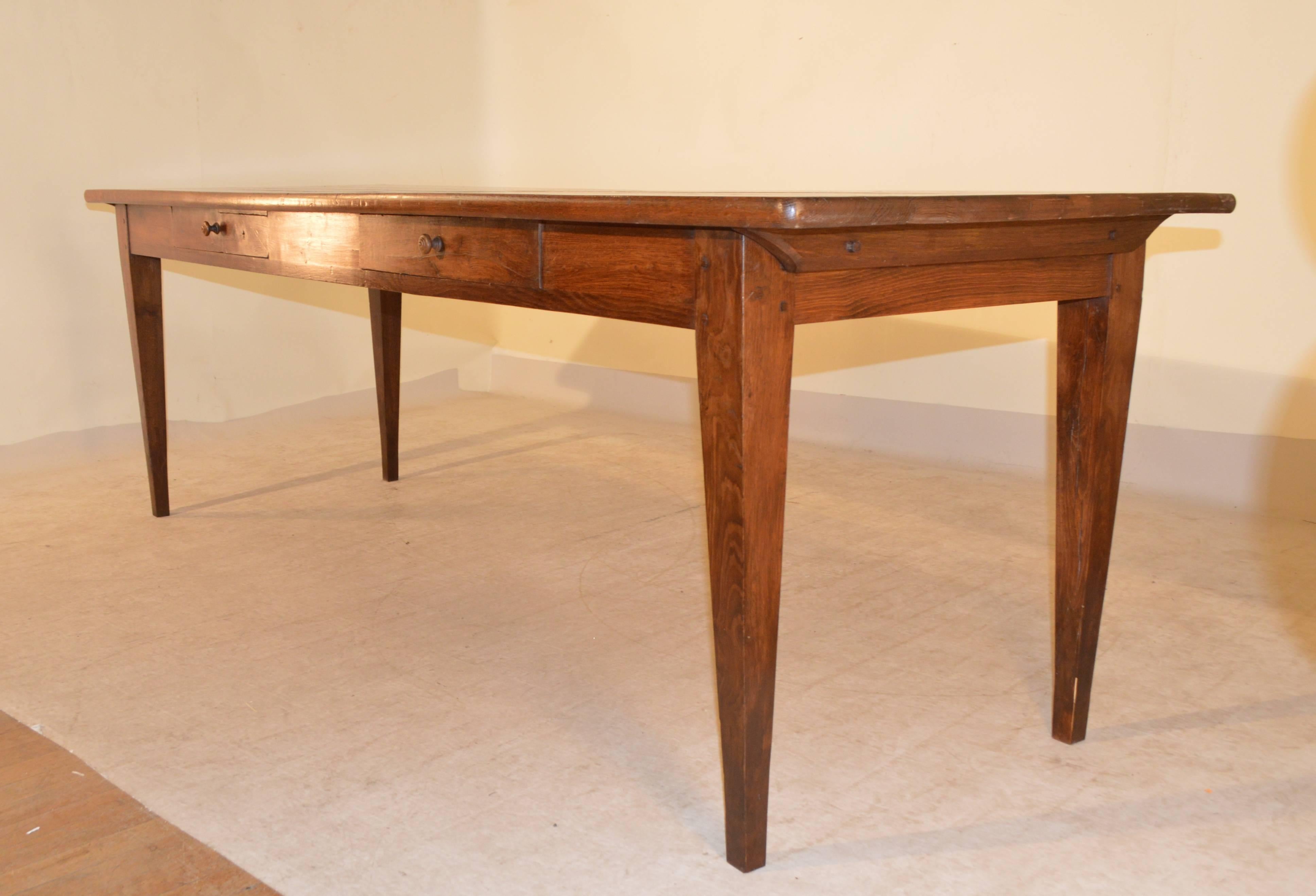 19th century French farm table with four plank top, following down to a simple apron containing two drawers, and tapered legs. One of the drawers has a money box enclosure, which is really unusual. The apron measures 24.75