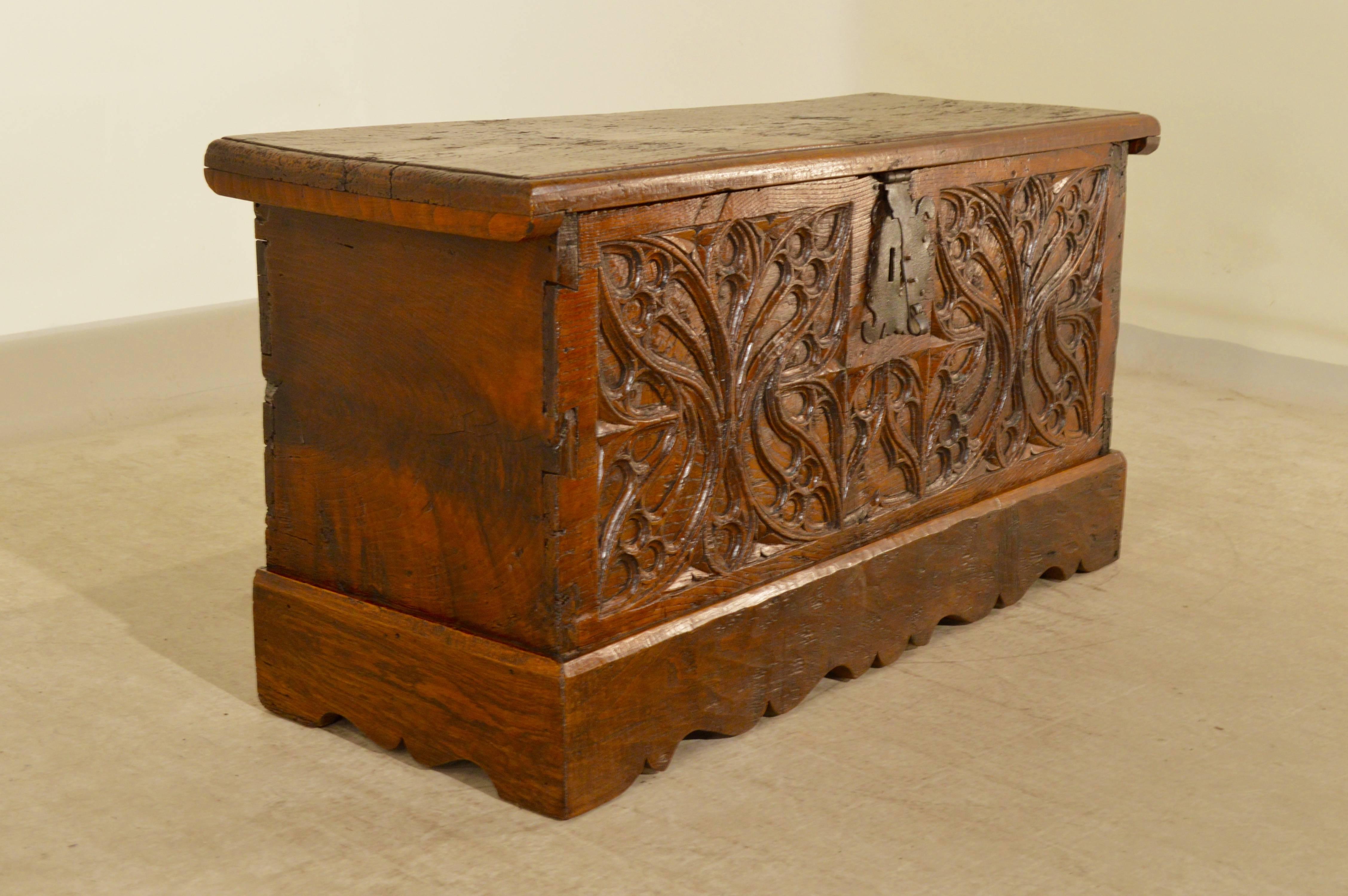 Early 17th century French blanket chest made from walnut. The top is made from a single plank of wood with a beveled edge. The piece is made up of five single planks, the front one being wonderfully deeply carved and resting on a hand scalloped base.
