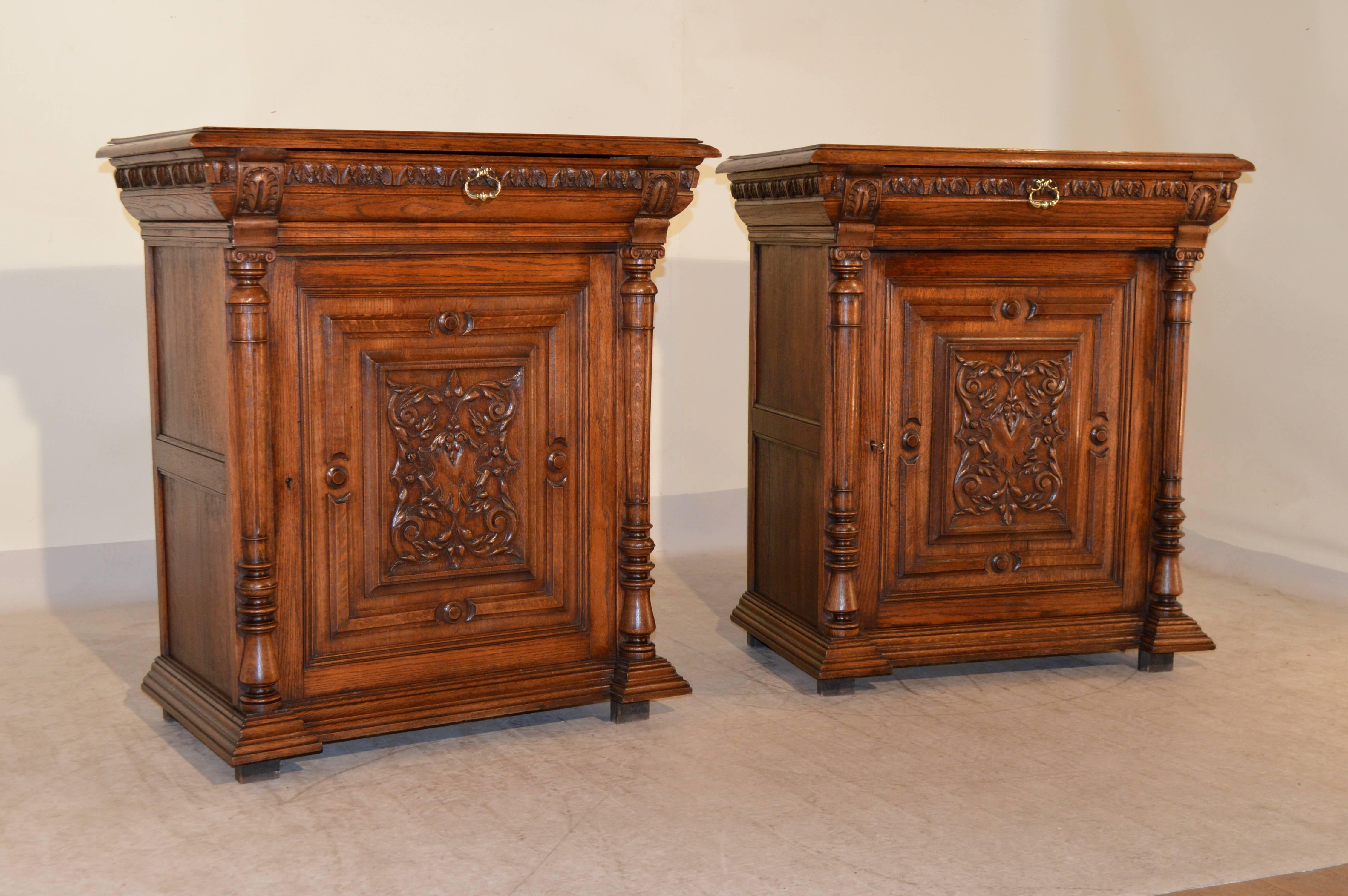 Pair of 19th century French oak cabinets with beveled edges around the tops, following down to a single molded drawer over a raised paneled and carved single door, which opens to reveal storage. The door is flanked by turned columns, and the case is
