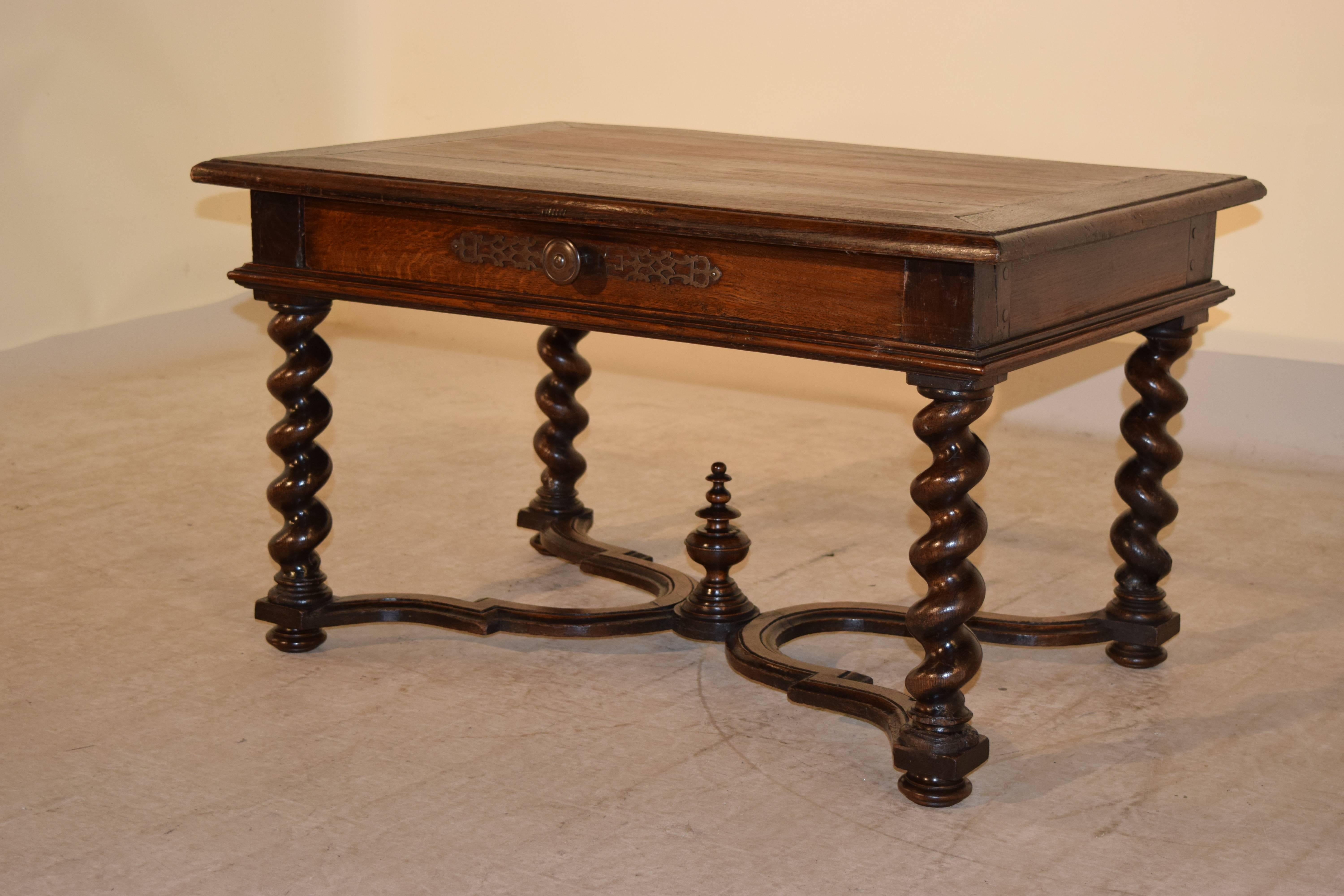 19th century French oak coffee table with a banded and beveled edge around the top. The apron is simple and has a single drawer, following down to a molded edge and raised on hand-turned barley twist legs joined by serpentine shaped stretchers with
