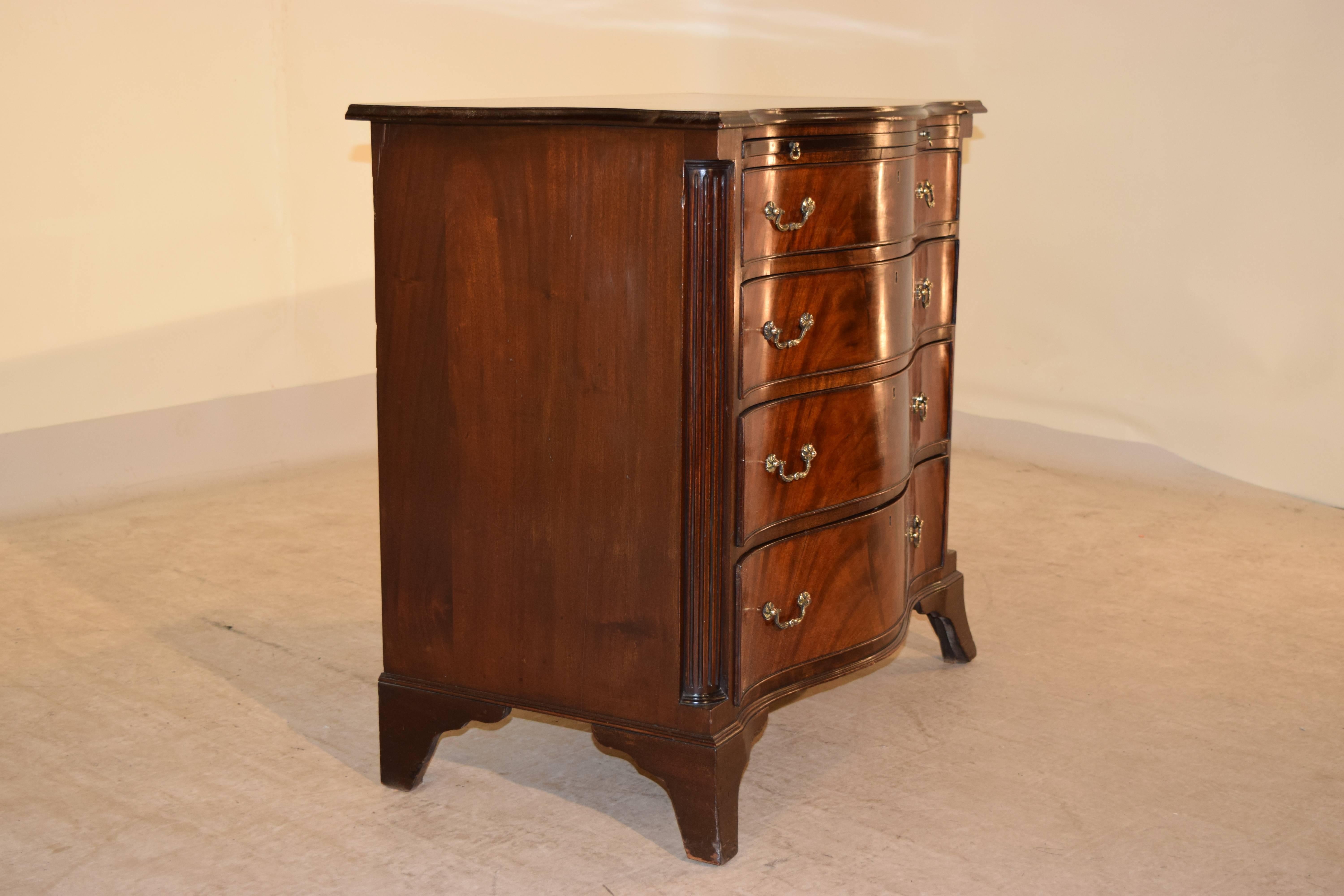 English mahogany small chest with a beveled edge around the top, following down to four graduated drawers, which are serpentine shaped and flanked by reeded columns. The case is raised on tall bracket feet, circa 1920.