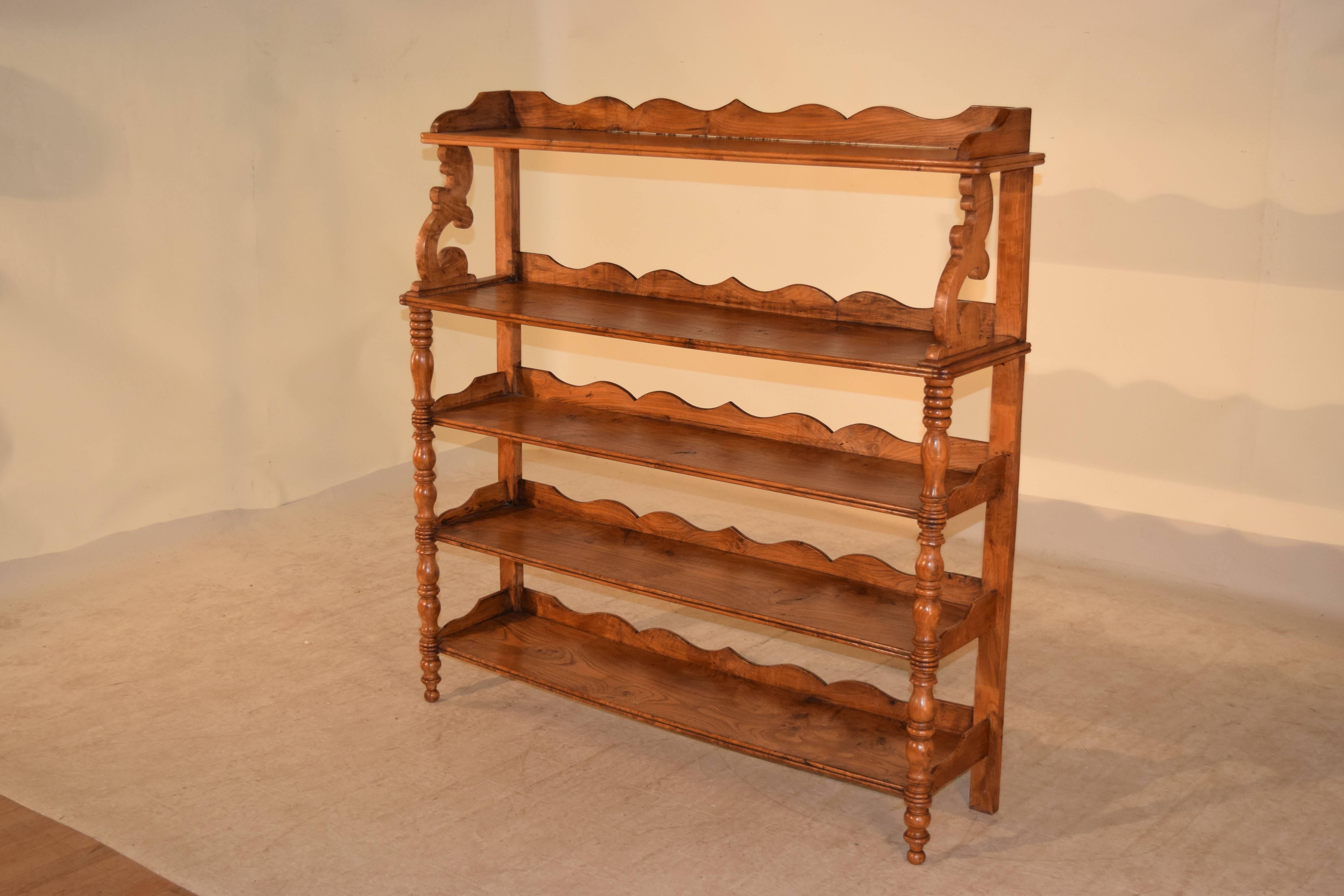 19th century English elm shelf with five shelves with lovely hand scalloped galleries and hand-carved and turned shelf supports. Raised on hand turned legs in the front and simple back legs for easy placement against a wall. The graining is