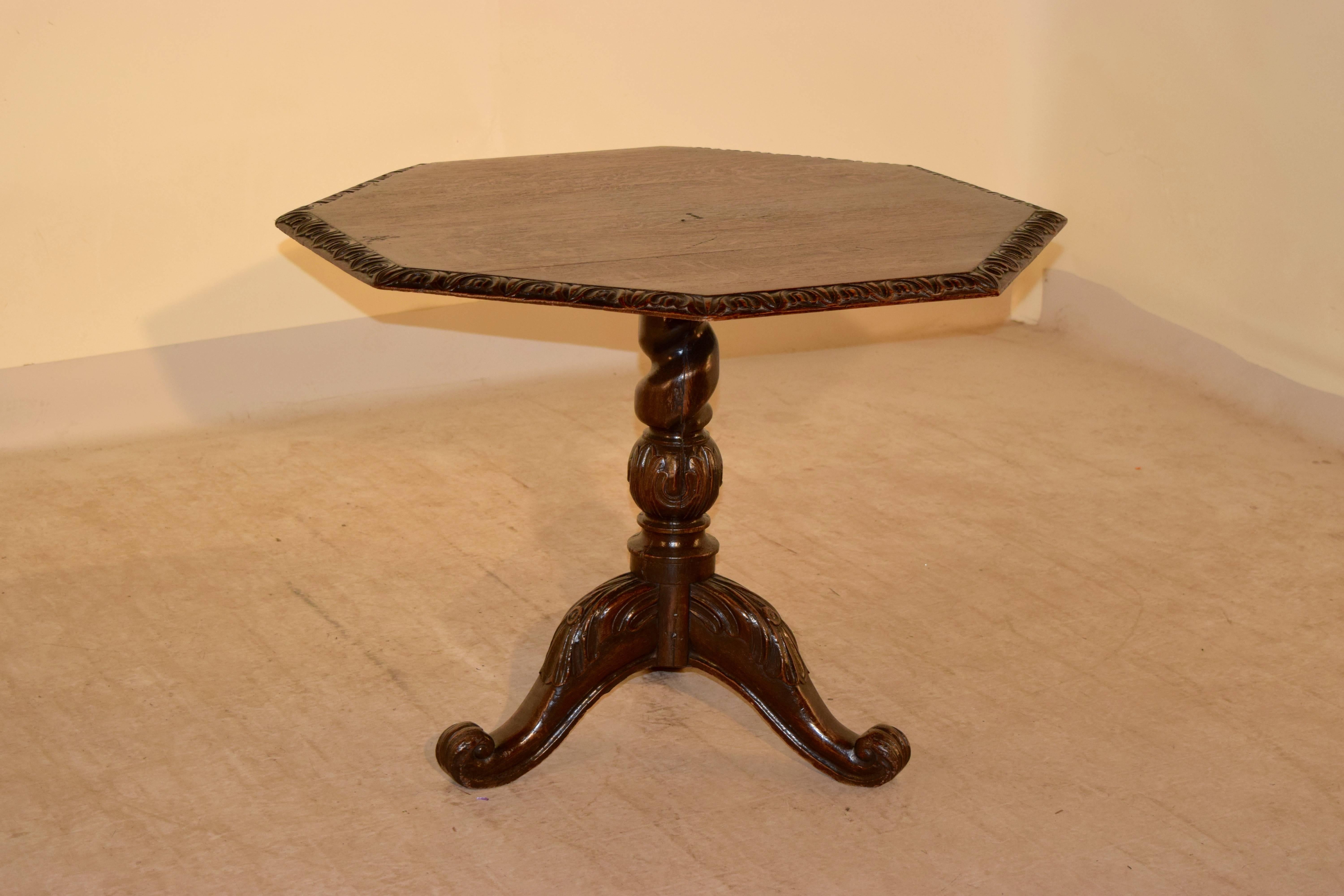 19th century English tilt-top table made from oak. The top has a beveled and wonderfully carved edge following down to a hand-turned barley twist and carved bulbous stem, supported on three hand-carved legs, which have carved decorated knees and end