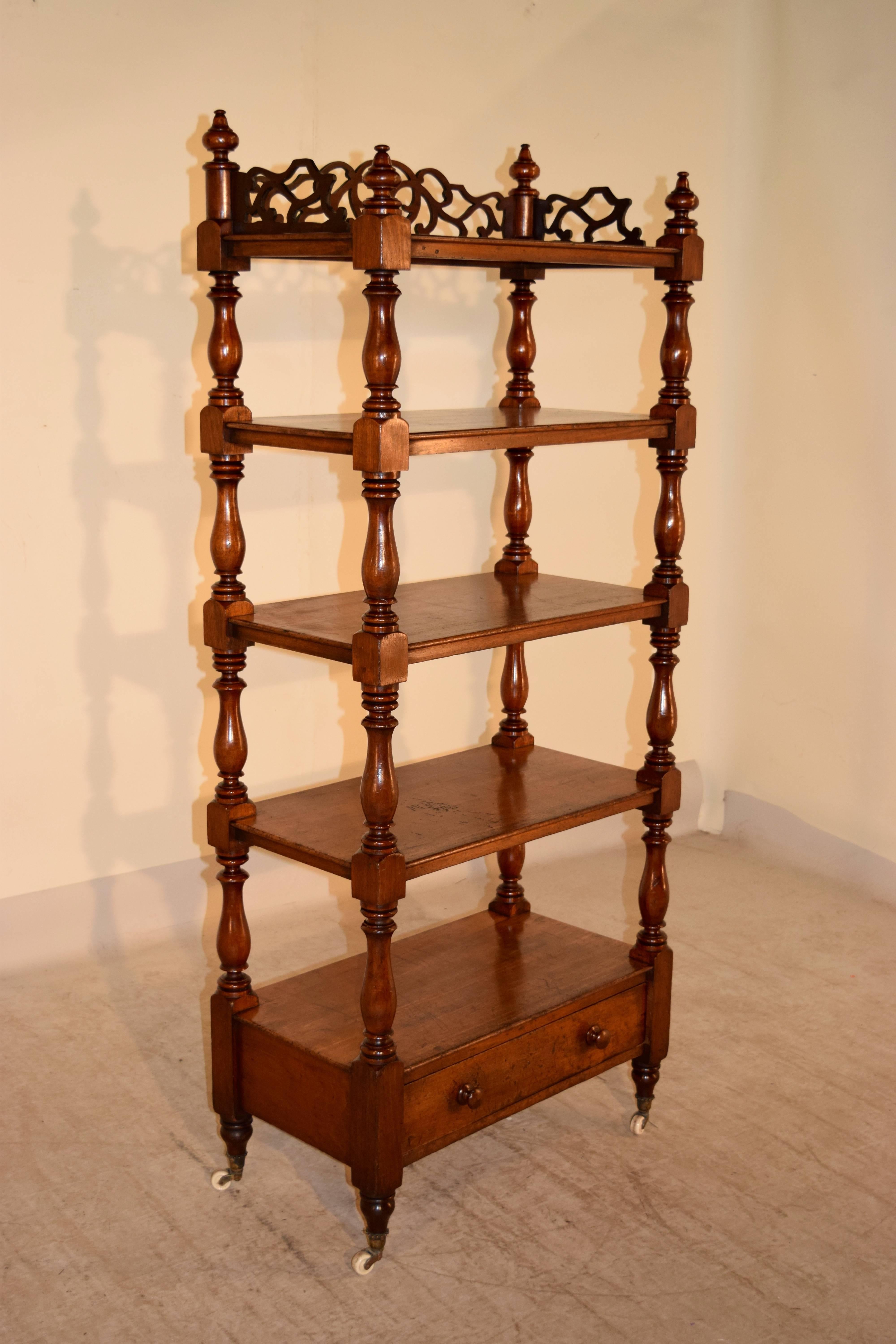 19th Century English mahogany etagere with wonderful fretwork around the top shelf, decorated with finials, following down to four lower shelves, with a drawer underneath. It has wonderfully hand-turned shelf supports and feet, which end in the