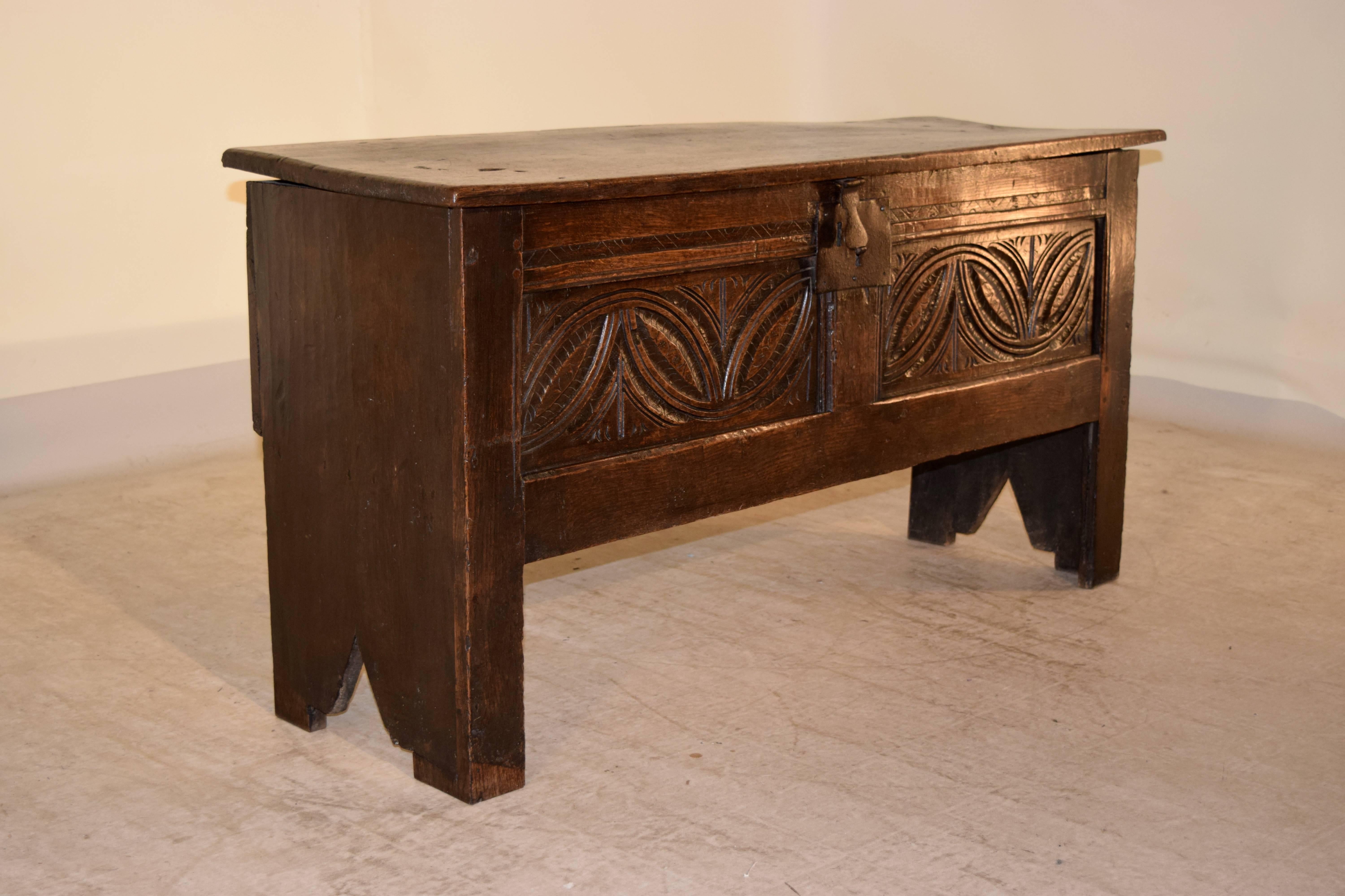 English oak sword chest, circa 1690-1720. The top is a single plank following down to a paneled front with hand-carved decorated panels and single plank sides with decorative patterned feet. The hardware appears to be original and made of iron.