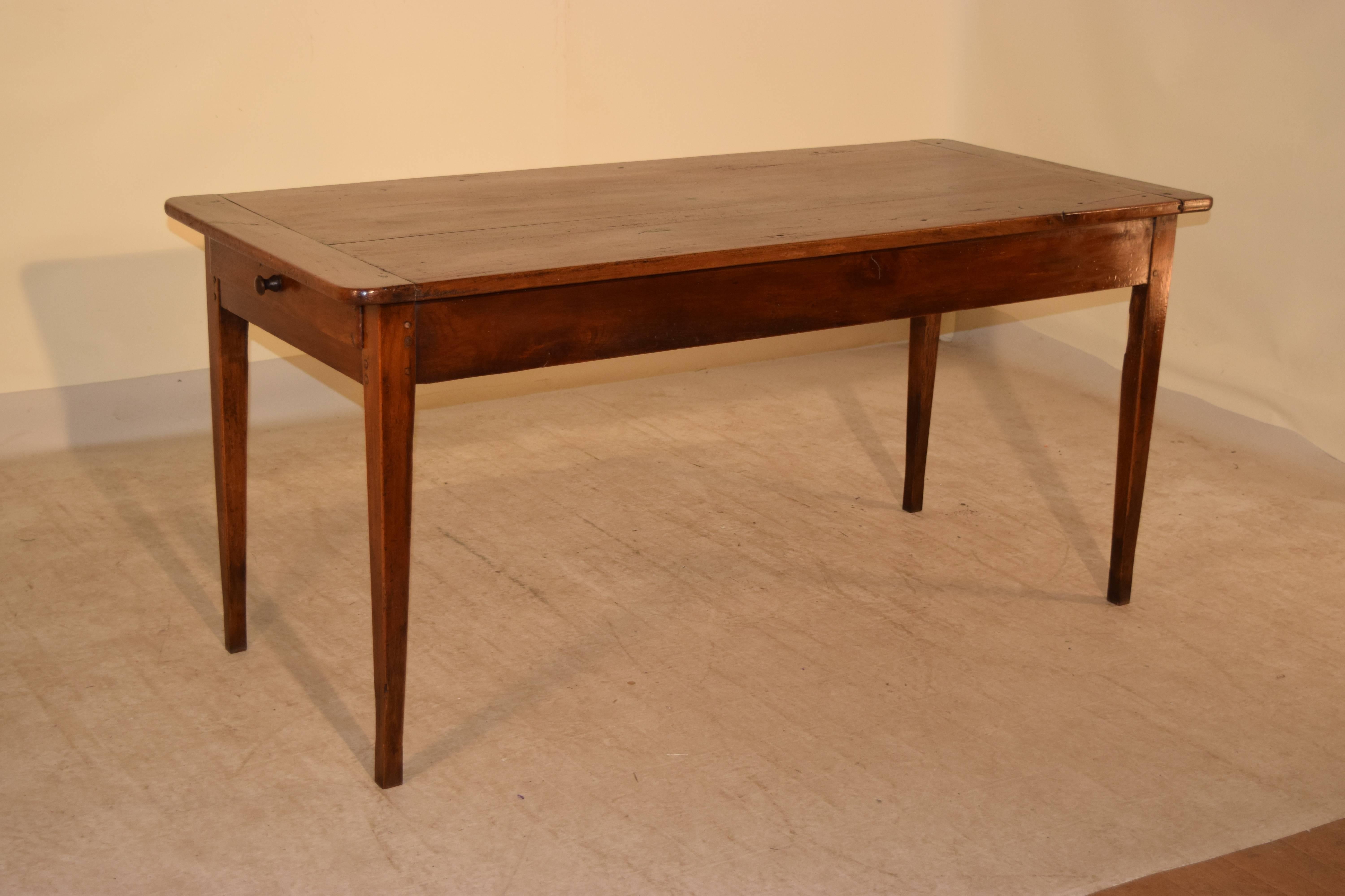 19th century French farm table made from cherry. The top is made of three planks with bread board ends, following down to a simple apron with a single drawer on one end and a bread board on the other which extends. The piece is raised on simple