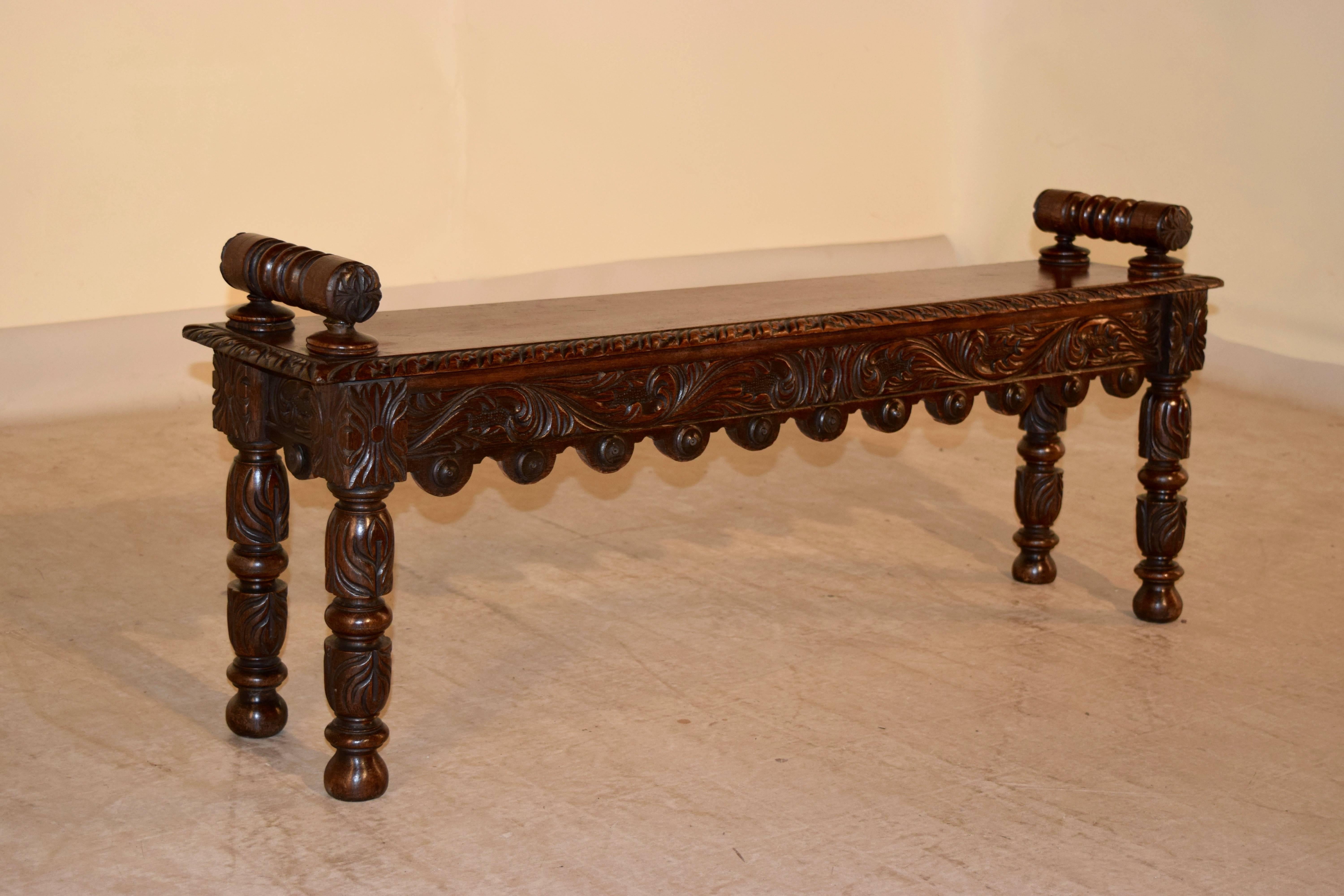 19th century English oak window seat with hand-turned handles attached to the seat, which has a beveled and gadrooned edge. The apron is also carved decorated and has a scalloped edge on the front. The piece is supported on hand carved legs.