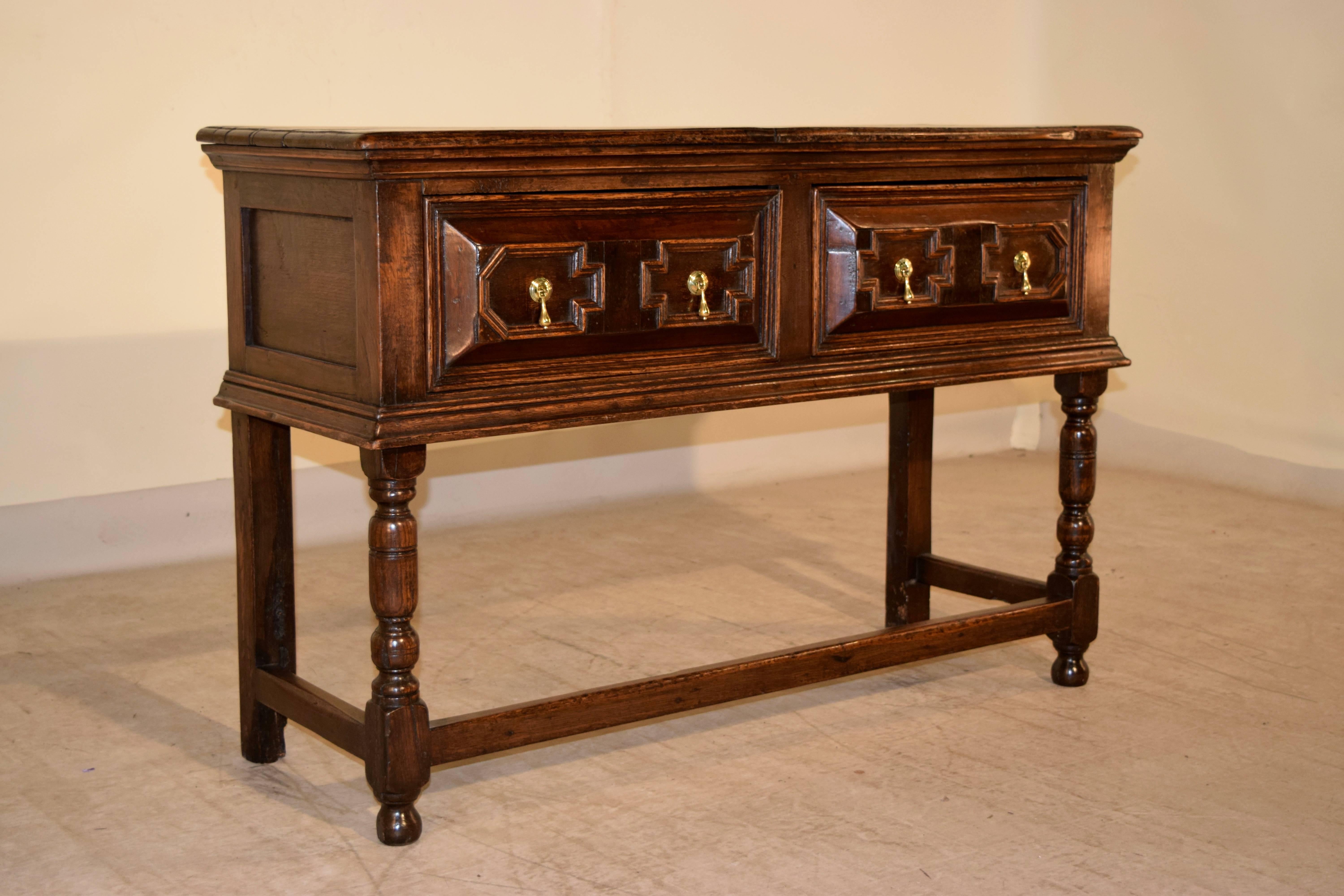 17th century English oak sideboard with a plank top, following down to panelled sides and raised panel geometric drawer fronts. The front legs are hand-turned and the back legs are squared for fitting against a wall. They are all joined by