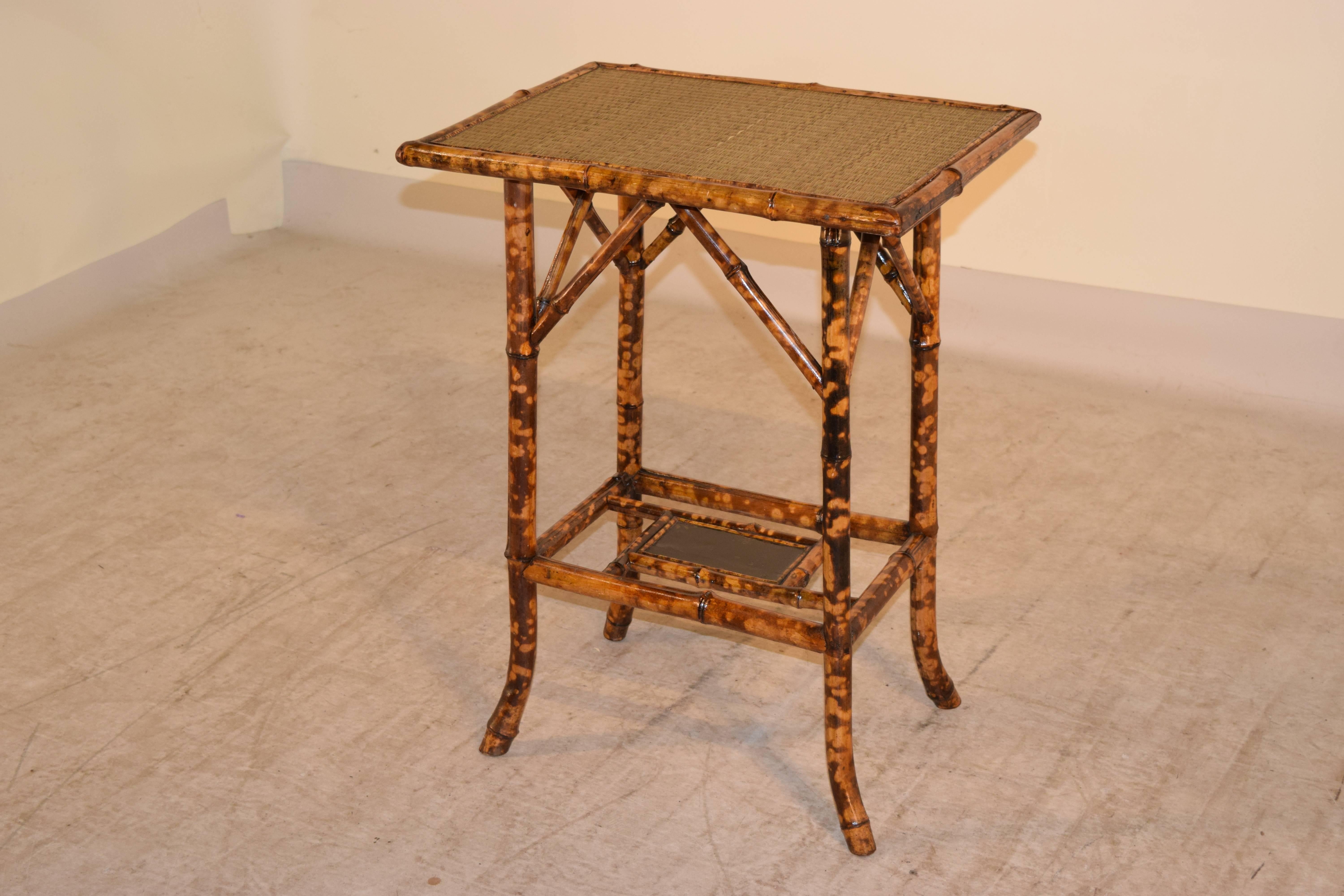 Late 19th century tortoise bamboo side table from France. The top is covered in rush, and the lower shelf is lacquered. The legs end in splayed feet for extra flair.