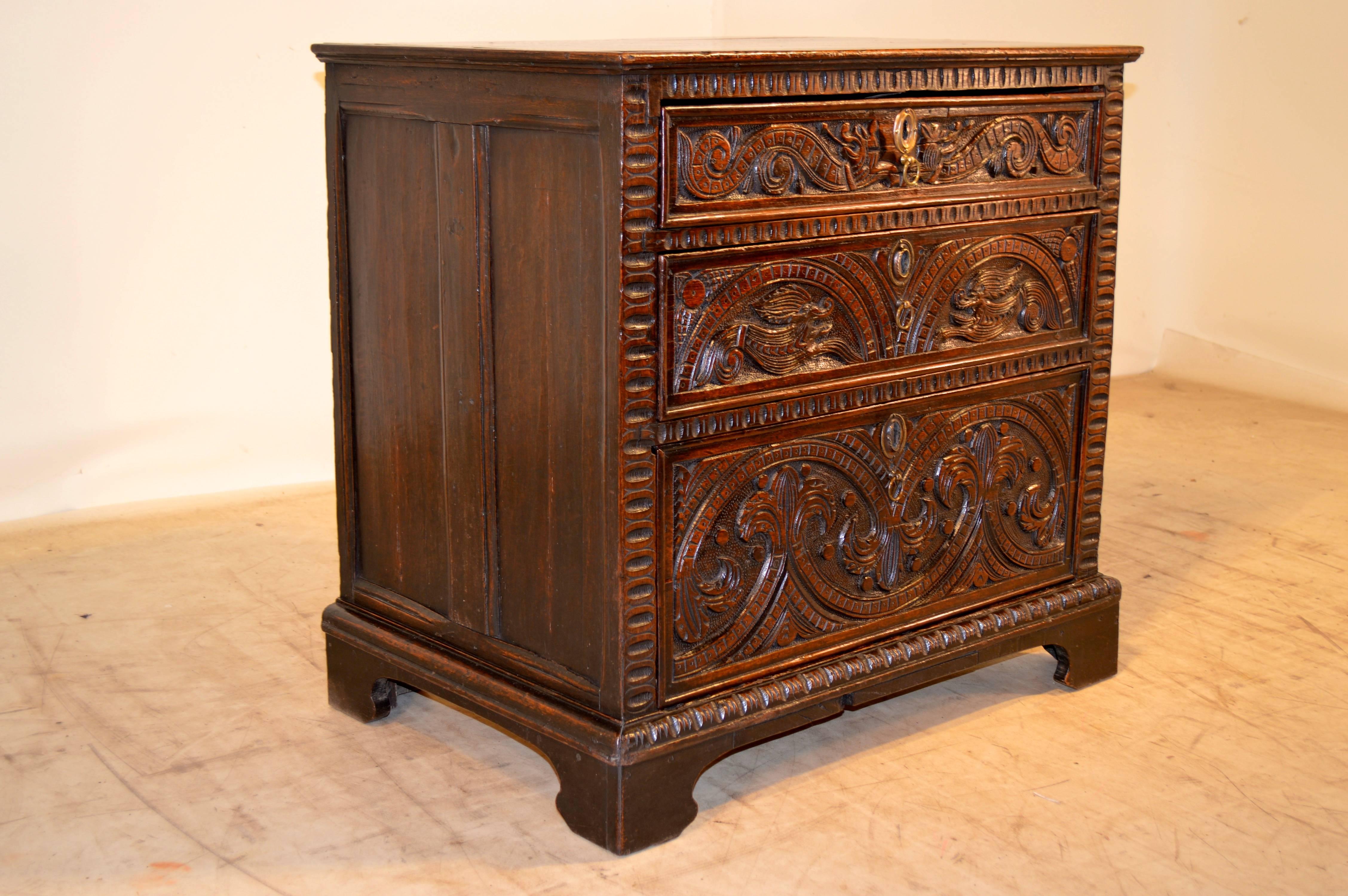 17th century English oak chest with carved decoration, beveled-edge top, hand-paneled sides, and three graduated drawers with carving on the fronts. The case is raised on bracket feet, circa 1650.