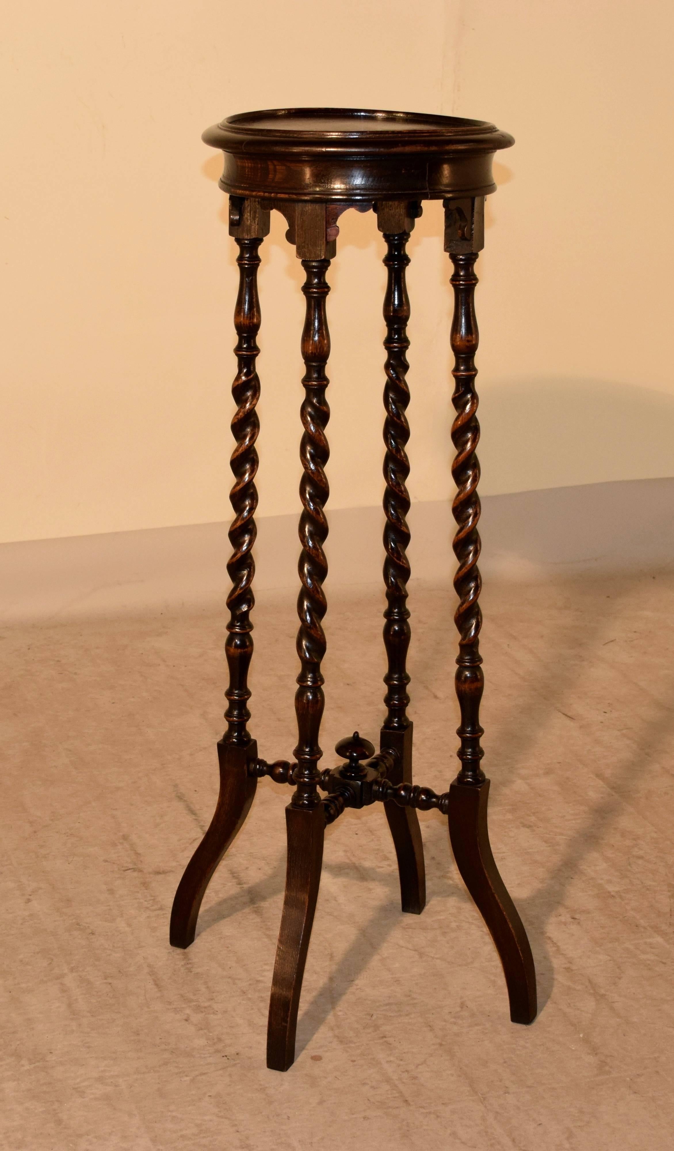 Late 19th century English oak plant stand with a molded rim around the top, following down to a wide apron, which also has a molded edge. The piece is supported on hand-turned barley twist legs, joined by turned cross stretchers, embellished with a