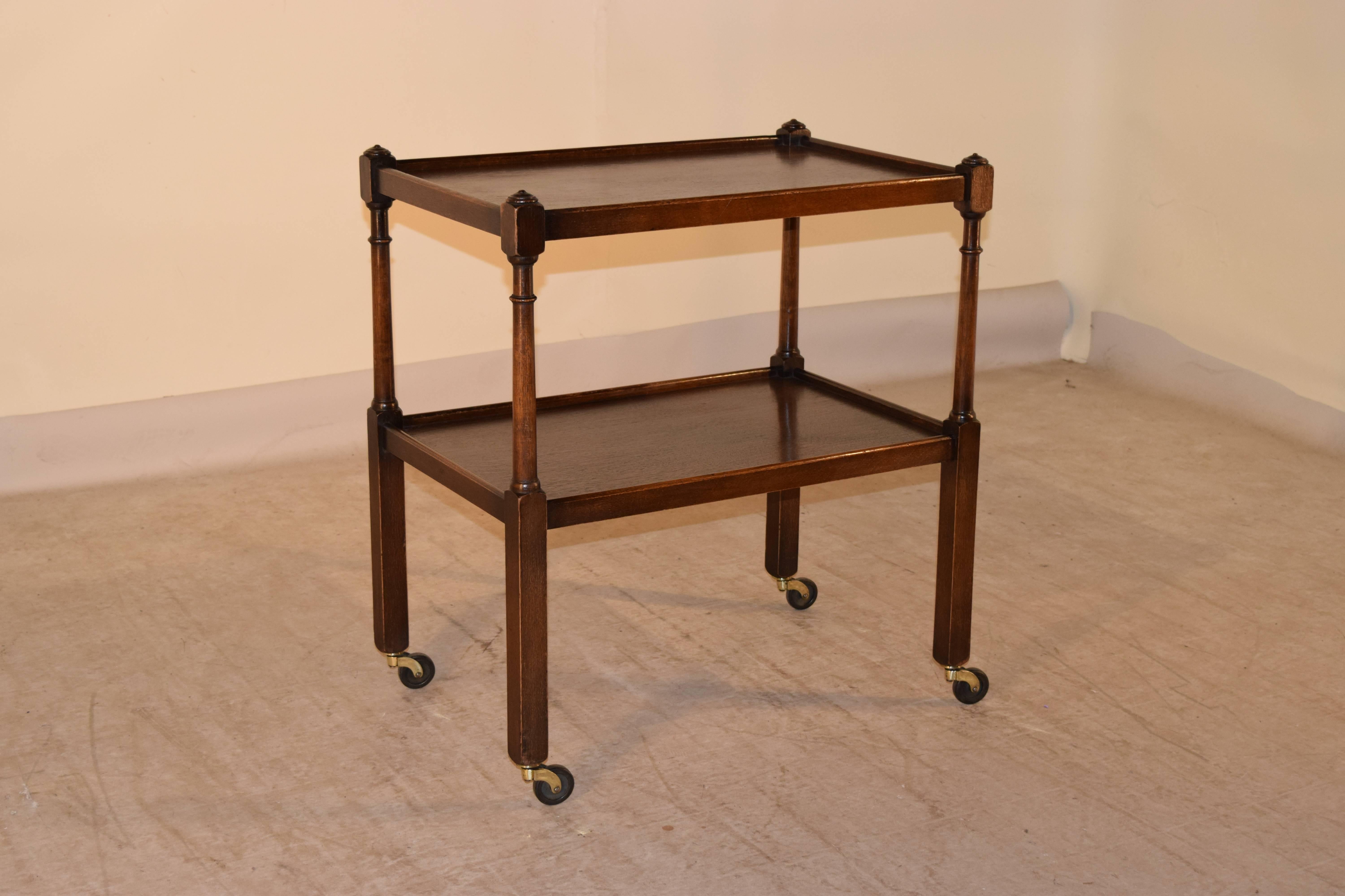 Late 19th century English oak drinks cart with two shelves, joined by hand-turned legs. Supported on casters.