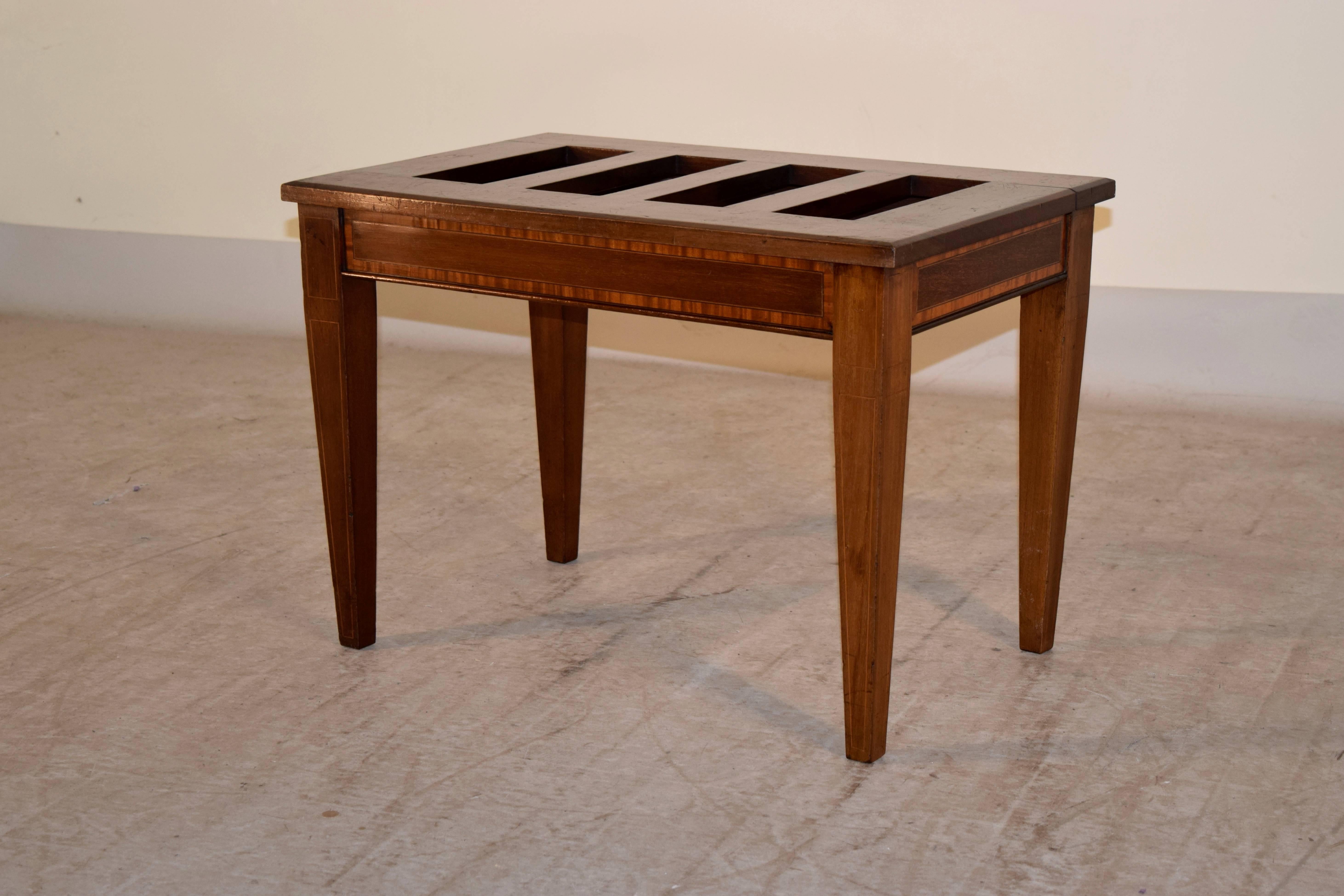 Late 19th century mahogany luggage stand from England. It has a slatted top, following down to a simple apron with satinwood banding and tapered legs.