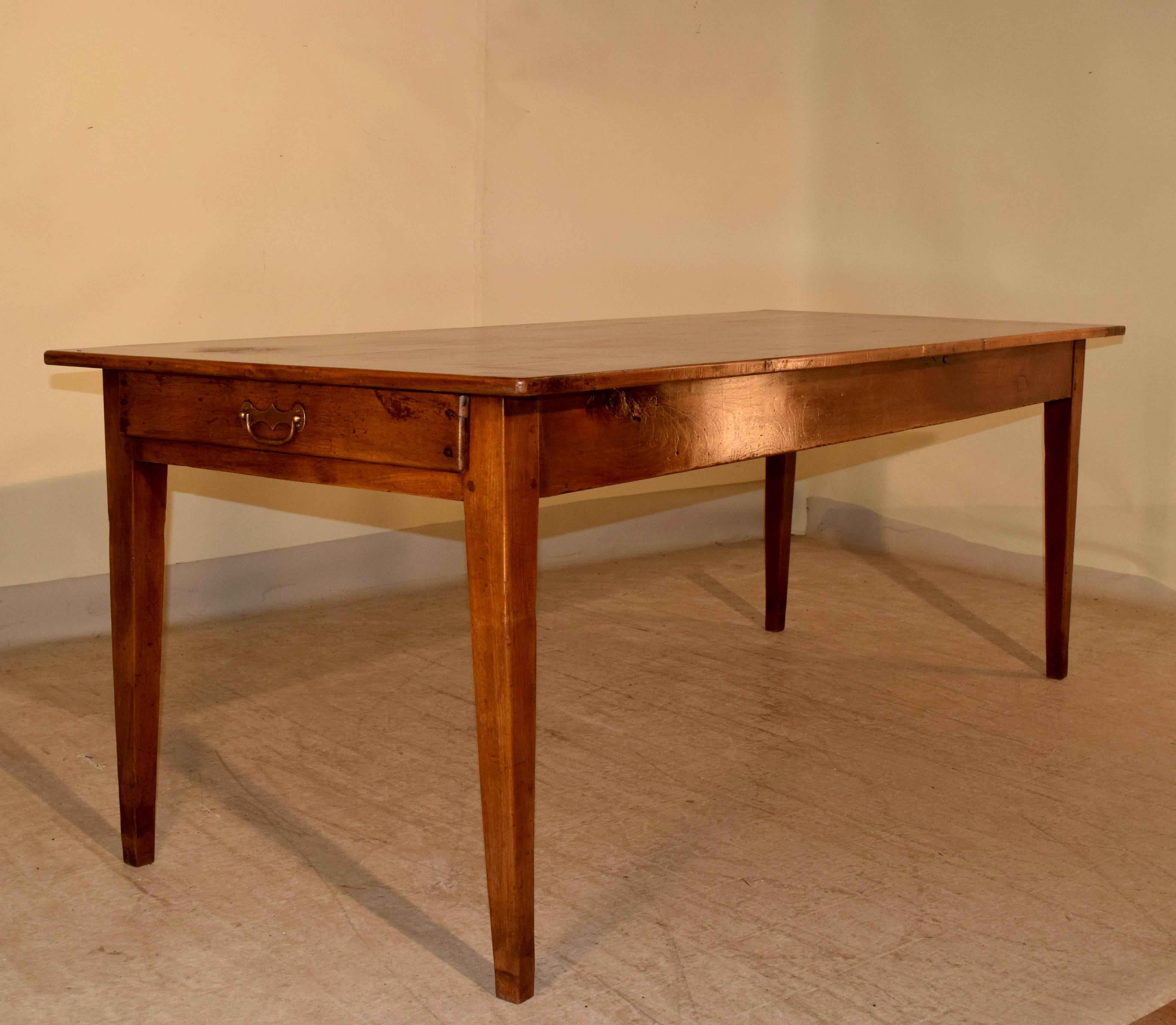 19th century French farm table made from cherry with a banded plank top, simple apron containing a drawer on one end and a bread board on the other end. The legs are tapered and the apron measures 24.13