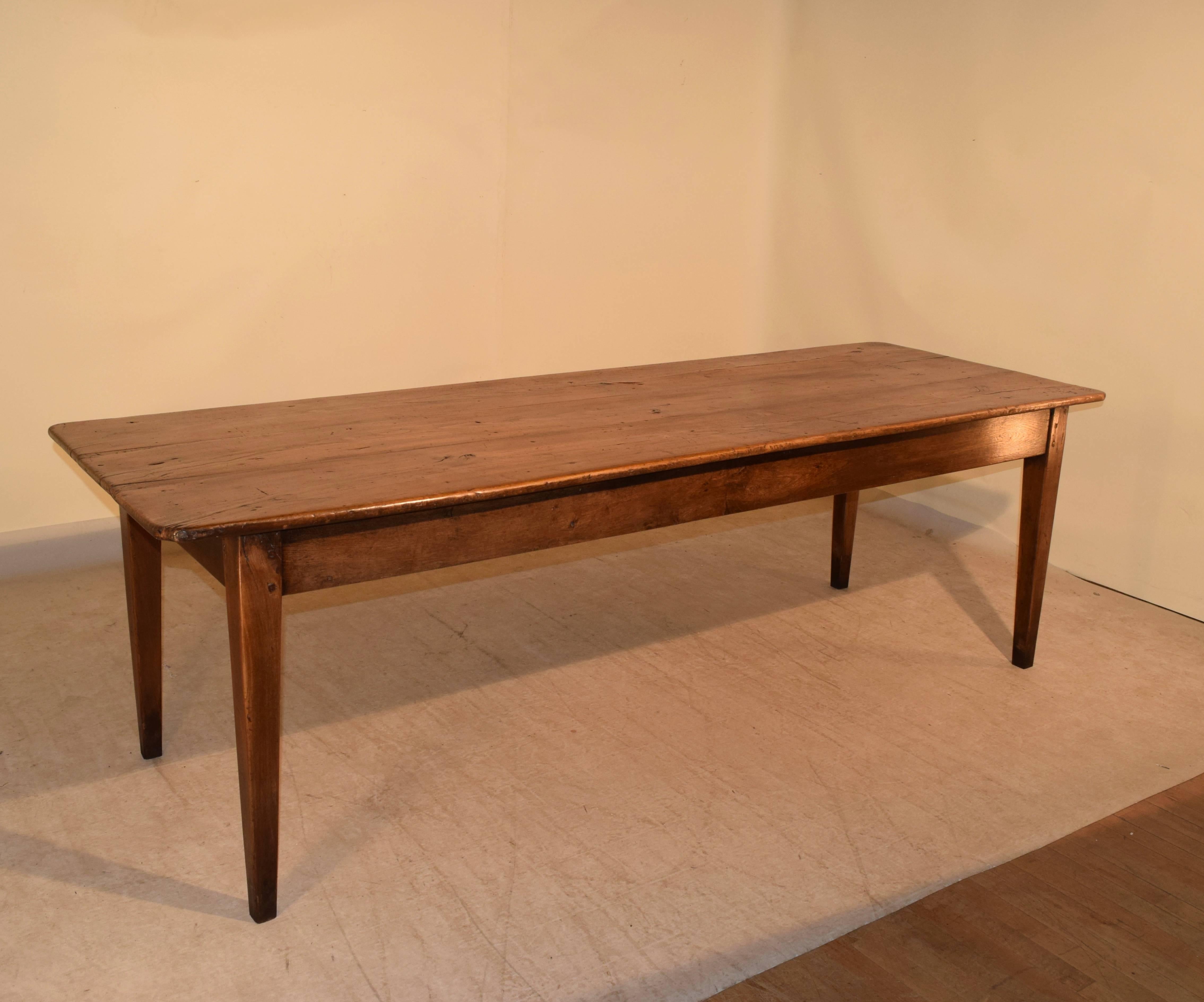 19th century French farm table made from walnut. The top is made up of planks and follows down to a simple apron, and is supported on tapered legs. The apron measures 23.88