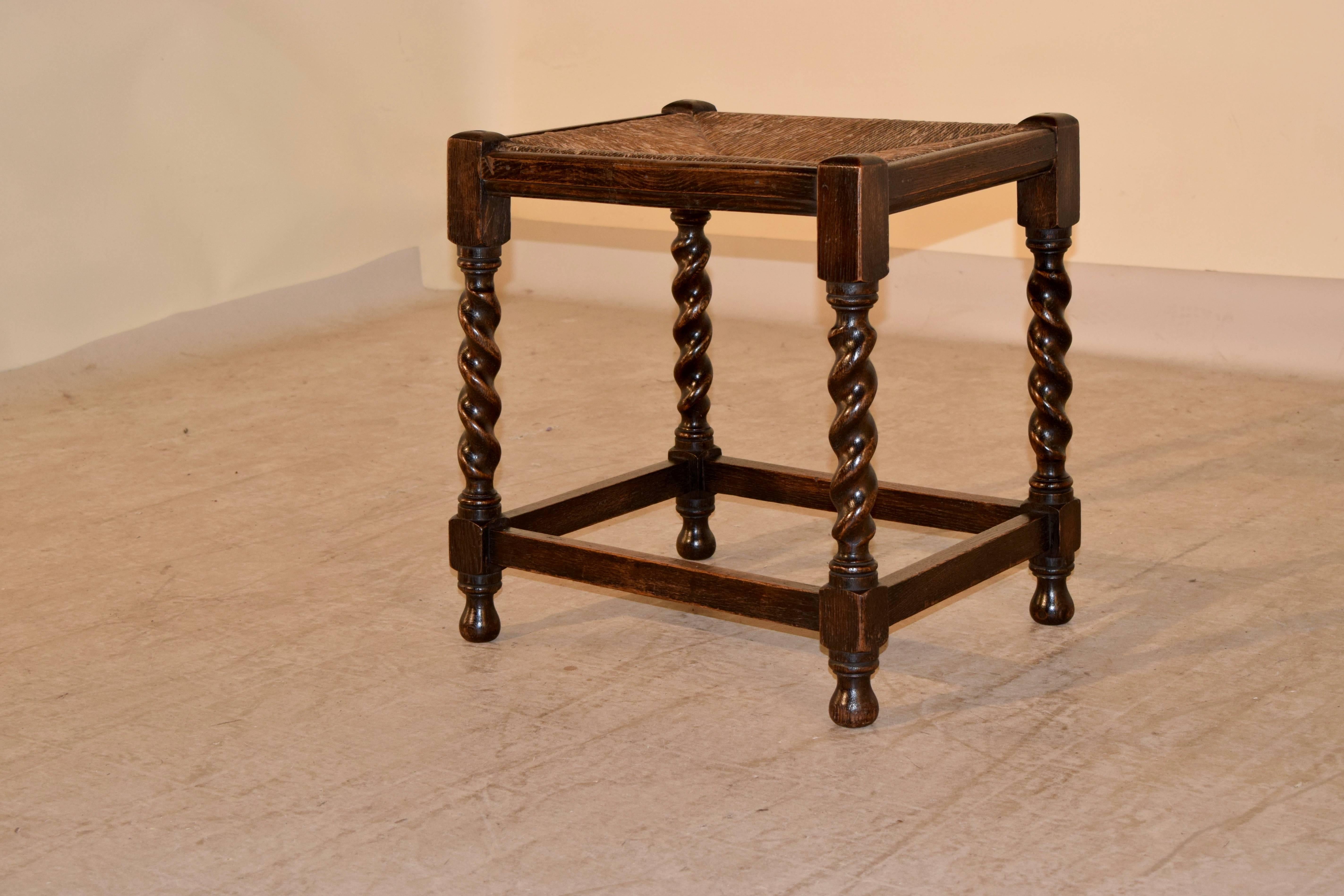19th century English oak stool with hand-turned barley twist legs, joined by simple stretchers and a handwoven rush seat.