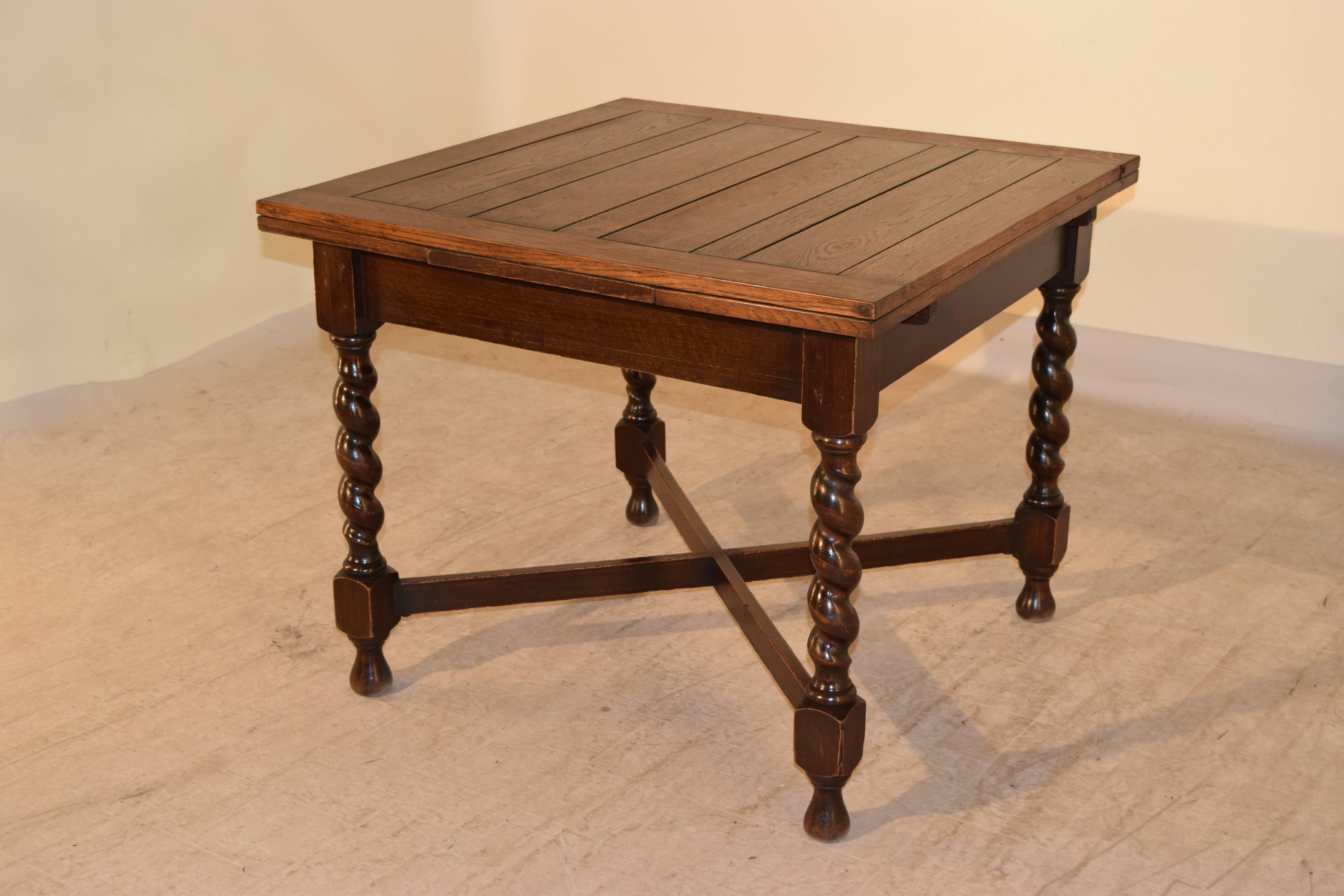 English oak draw leaf table with a paneled top and leaves, following down to a simple apron and supported on hand-turned barley twist legs, joined by cross stretchers, circa 1900. Raised on turned feet. Apron, 23
