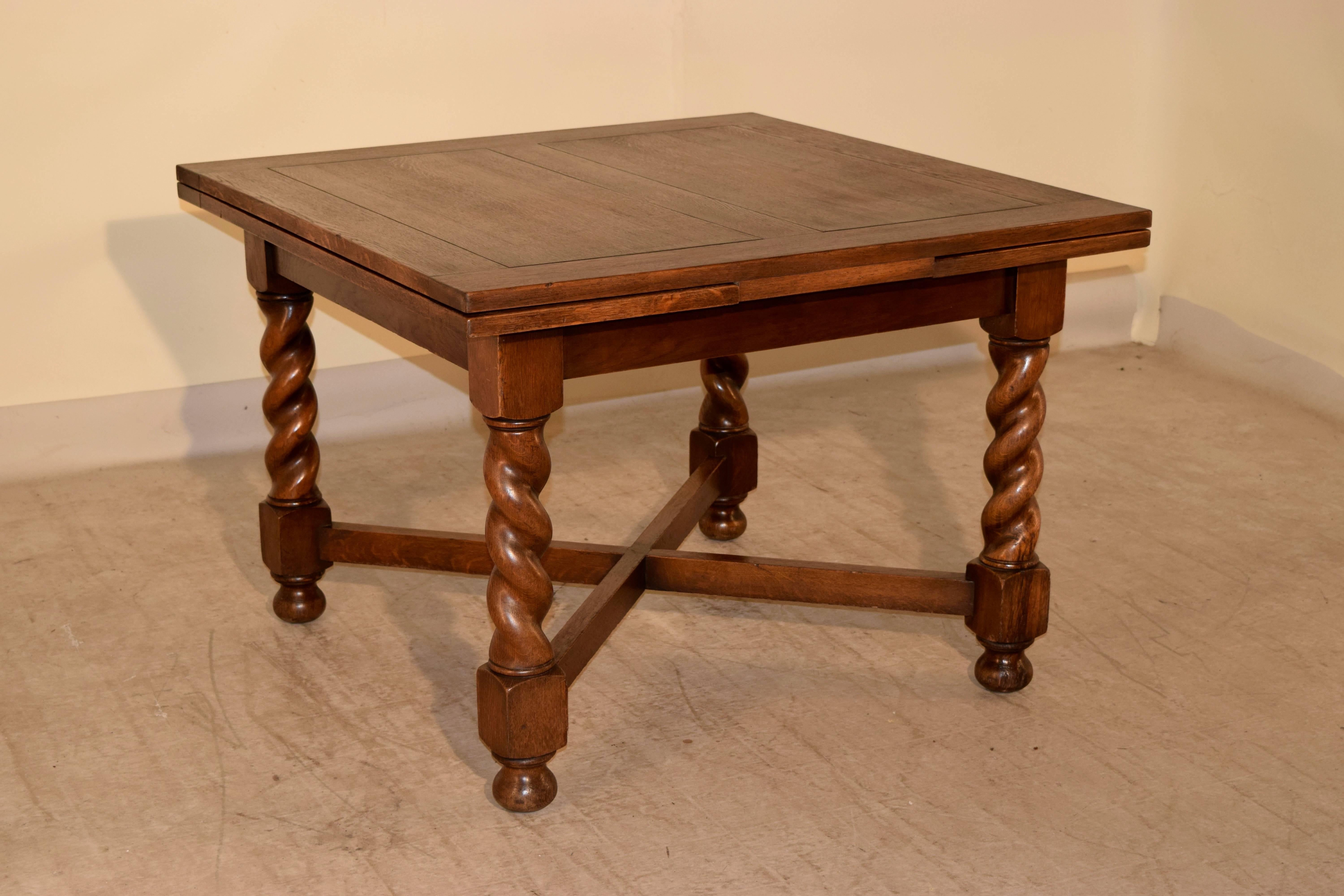 English oak draw-leaf table of larger size, circa 1900. The top and leaves are paneled and follow down to a simple apron. The table is supported on thickly hand-turned barley twist legs, joined by cross stretchers and raised on turned bun feet.