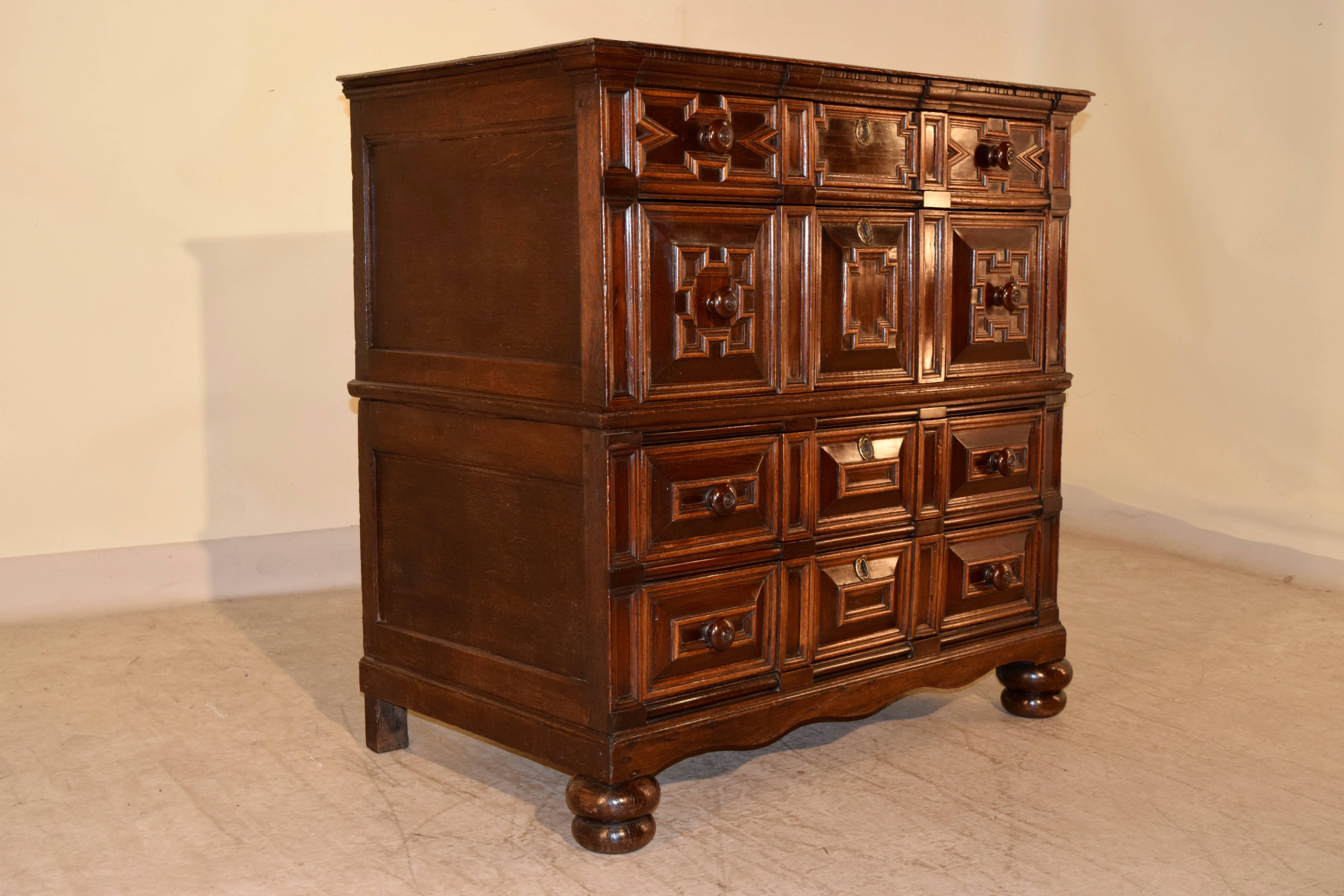 17th century unusual two-piece chest of drawers. The top is made up of oak planks, and has a beveled edge. There is old restoration, staining and discoloration on the top from honest use. There are four drawers, all with cushion panels and geometric
