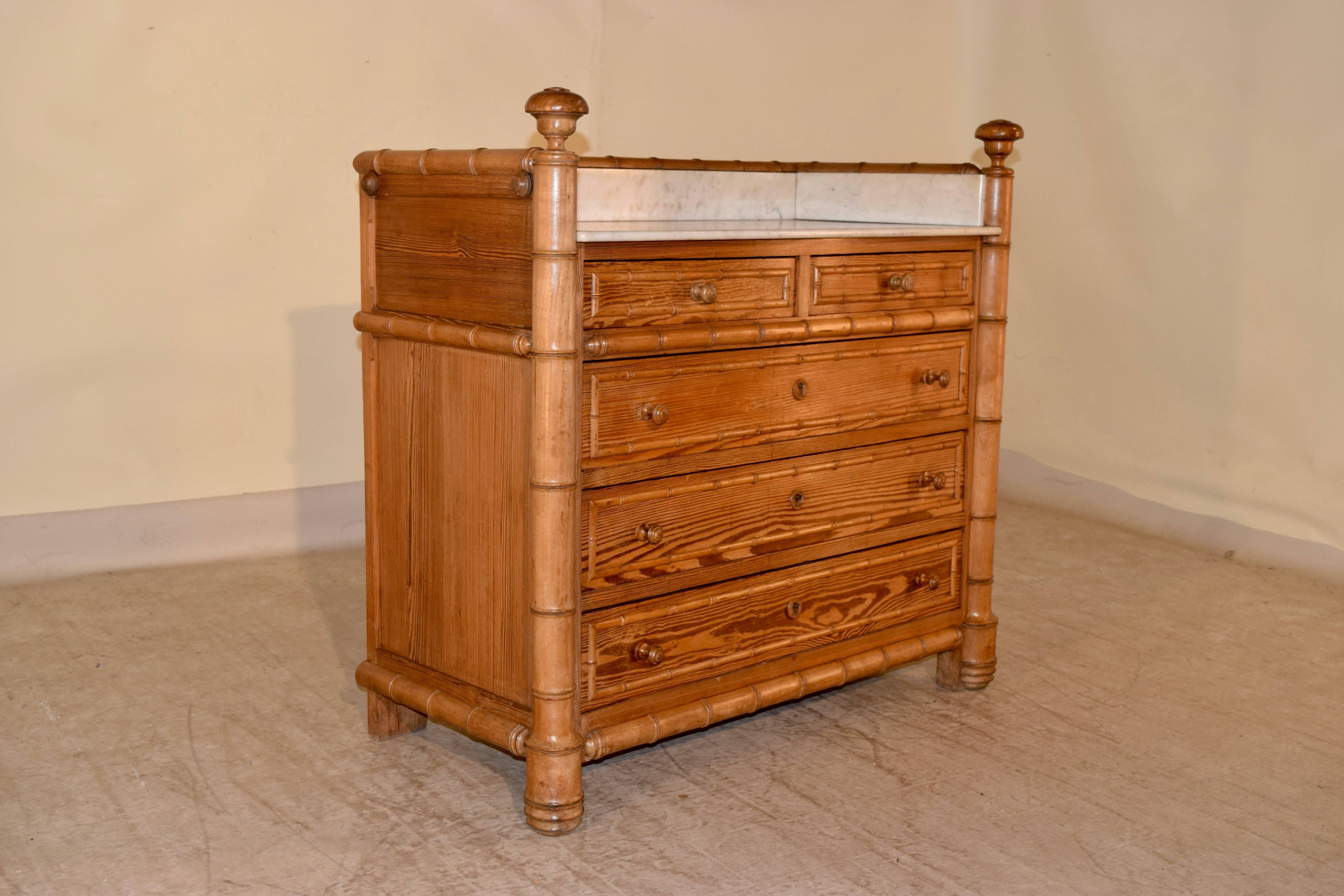 19th century French wash stand decorated with faux bamboo. The top is marble, and is surrounded by faux bamboo style moldings. The sides are paneled and the chest has a two drawer over three-drawer configuration, all banded in faux bamboo moldings.