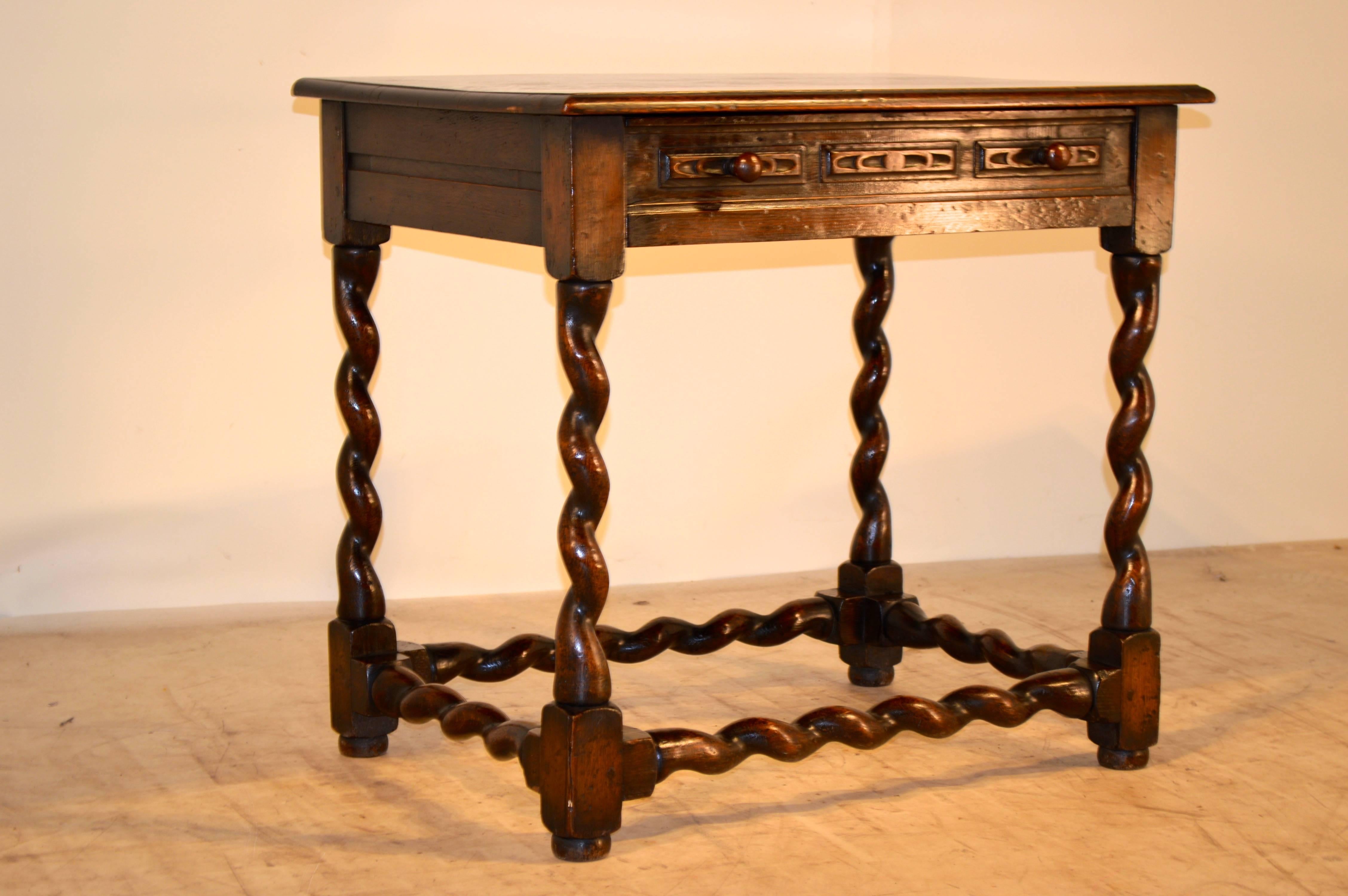 19th century English oak side table with a beveled edge around the top following down to channeled sides and a single drawer with hand-carved decoration. The legs and stretchers are an unusual version of a barley-twist.