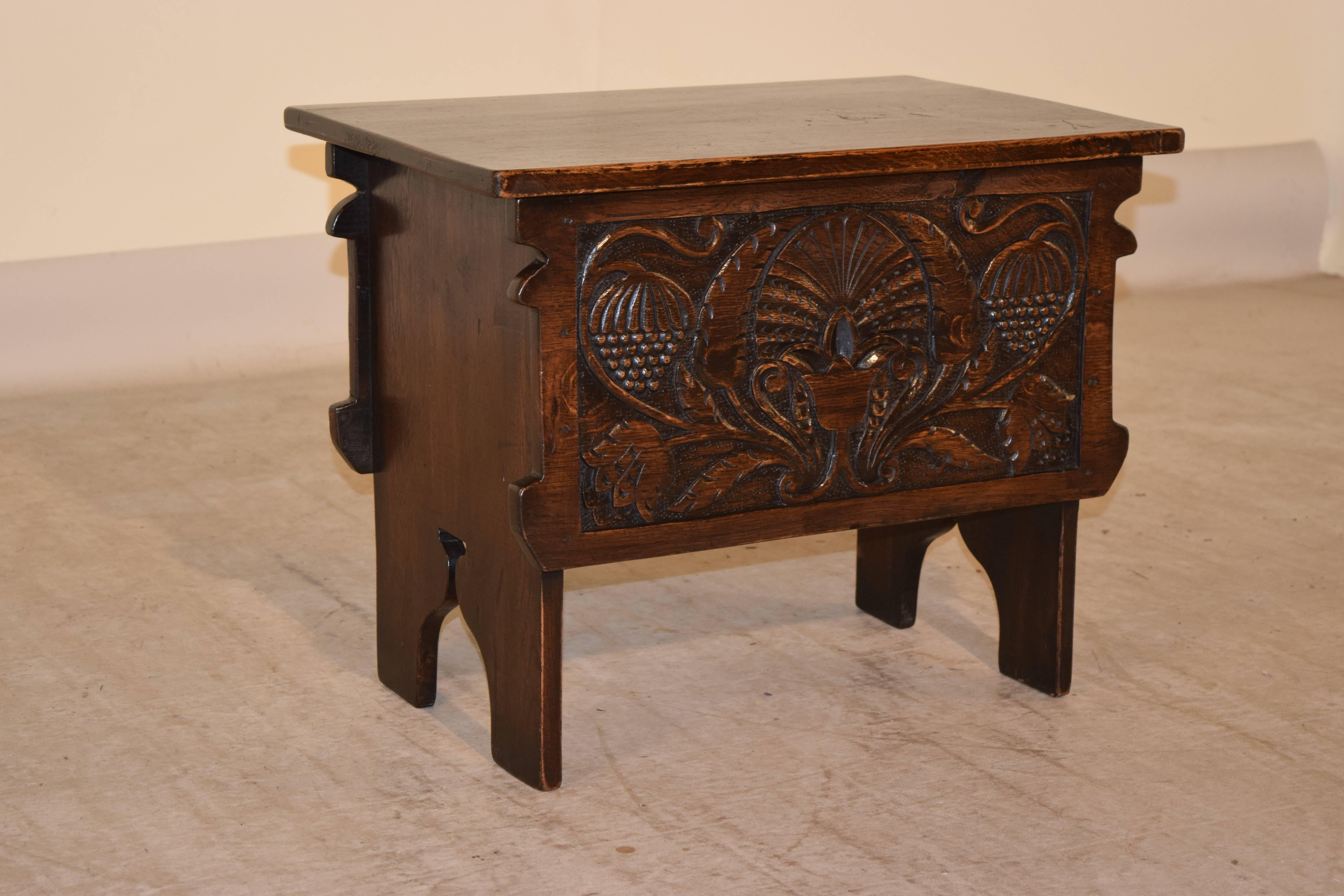 19th century English oak stool with a lift top. The front has lovely hand-carved decoration, and the sides are plank with scalloped feet.