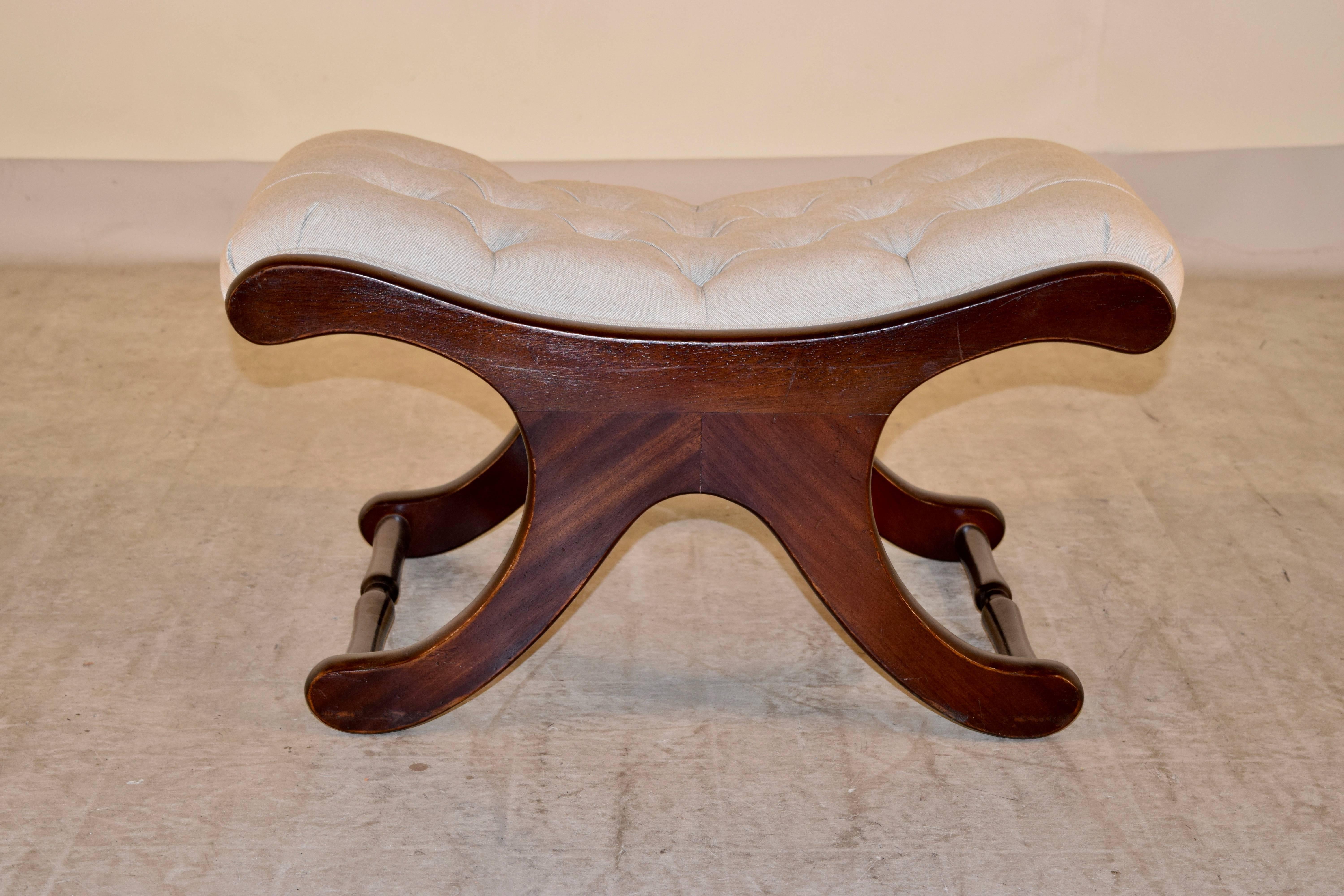 19th century English mahogany stool with a cross shaped frame. The legs are joined by turned stretchers and the stool has been newly upholstered in linen.