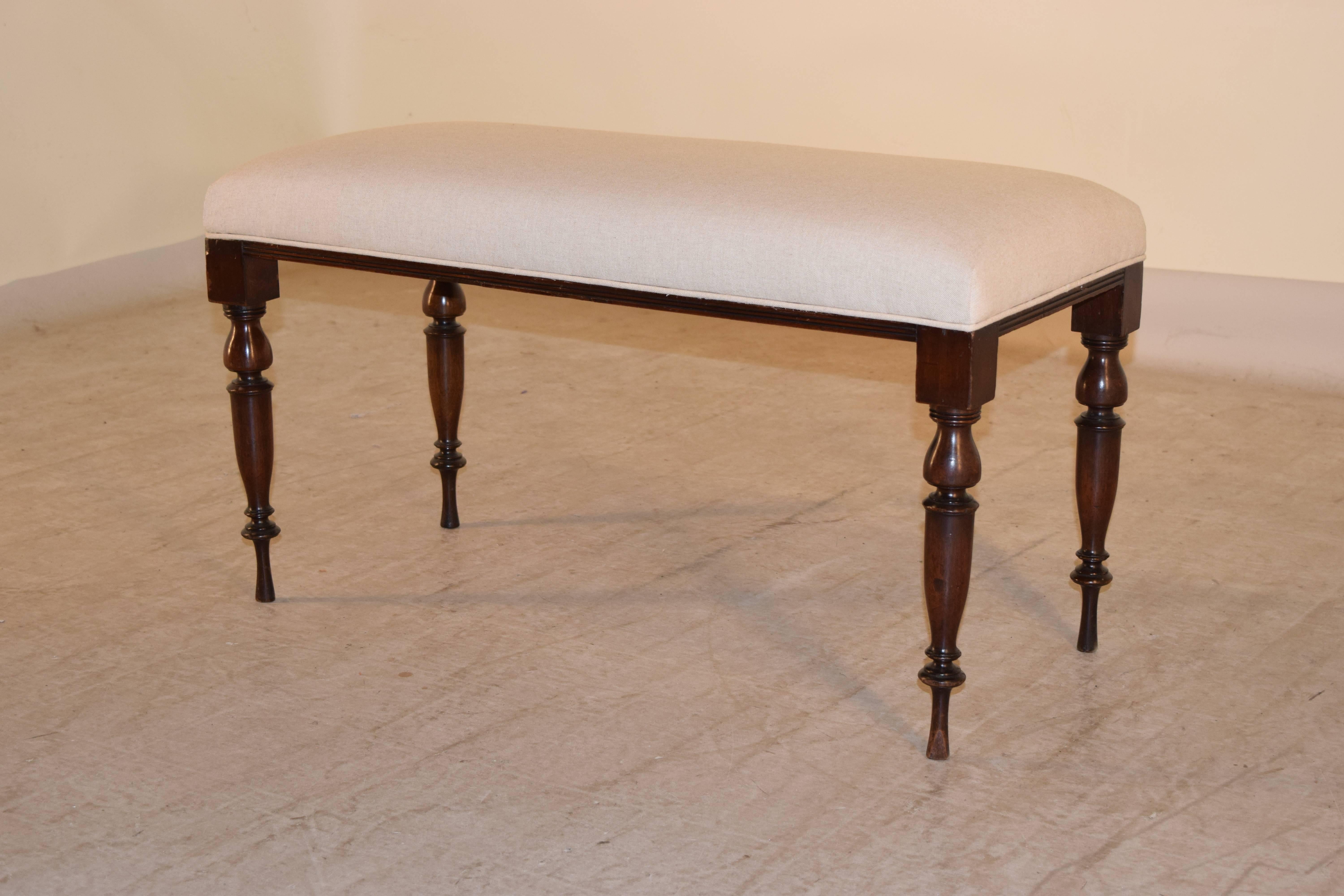 19th century English bench made from mahogany with lovely and elegantly hand-turned legs. Newly upholstered in linen and finished with a single welt.