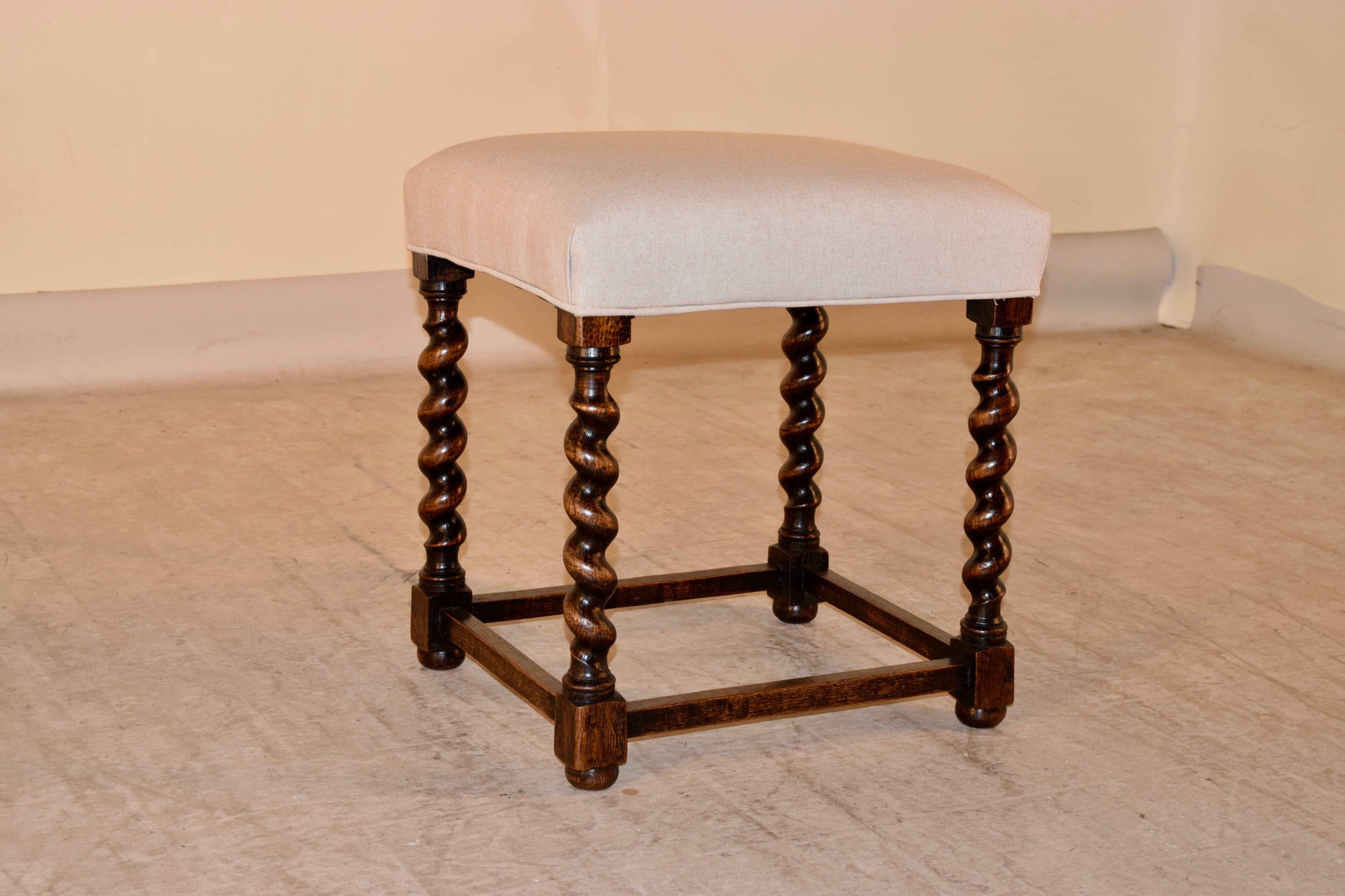 19th century, English oak stool with a newly upholstered top in linen and finished with a single welt. The base has nicely hand-turned barley twist legs joined by simple stretchers and supported on turned feet.
