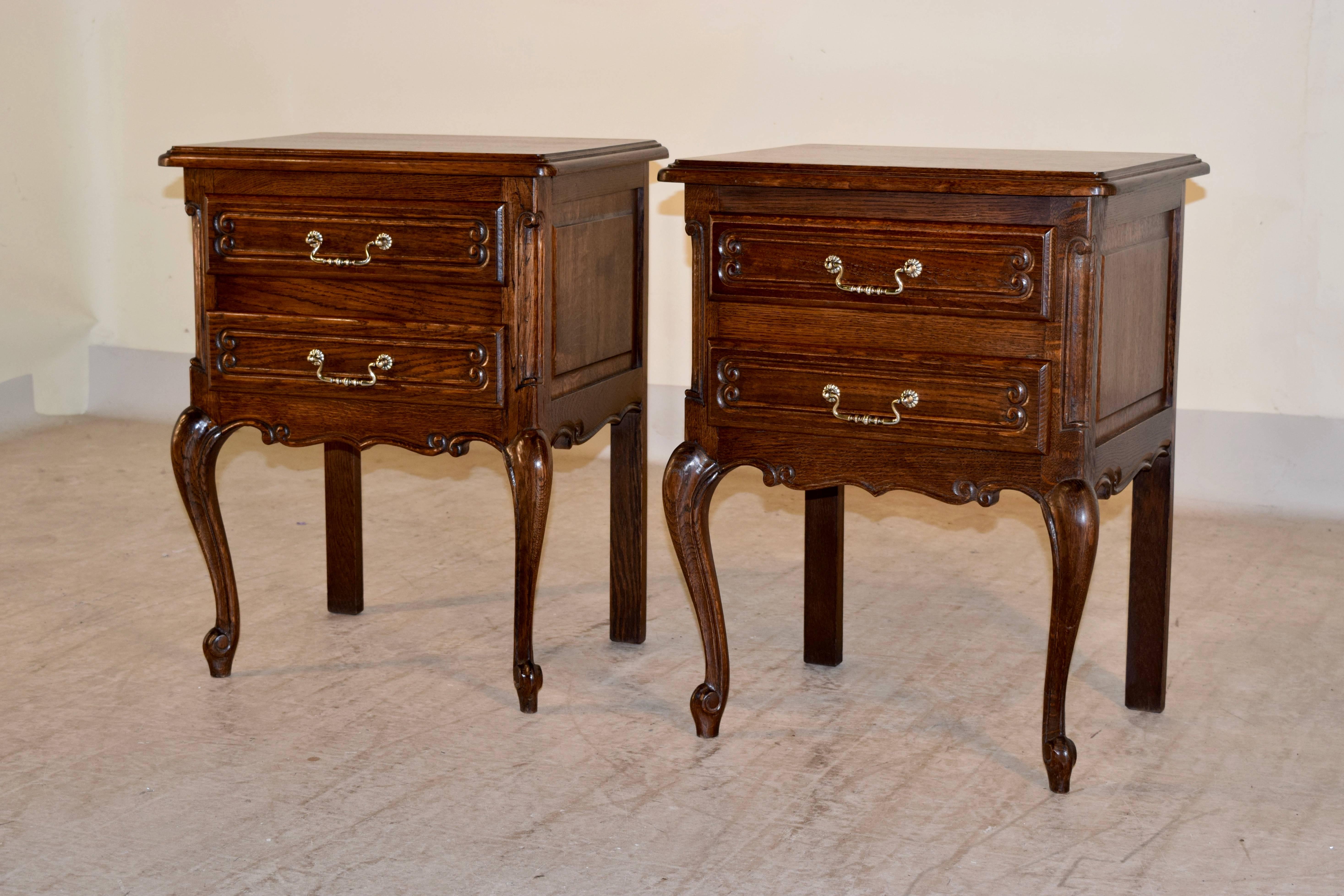 Pair of French side tables made from oak, circa 1930s. Nicely beveled edges around the tops, following down to a case with raised paneled sides and containing two drawers in the front. Supported on cabriole legs which end in scroll feet in the