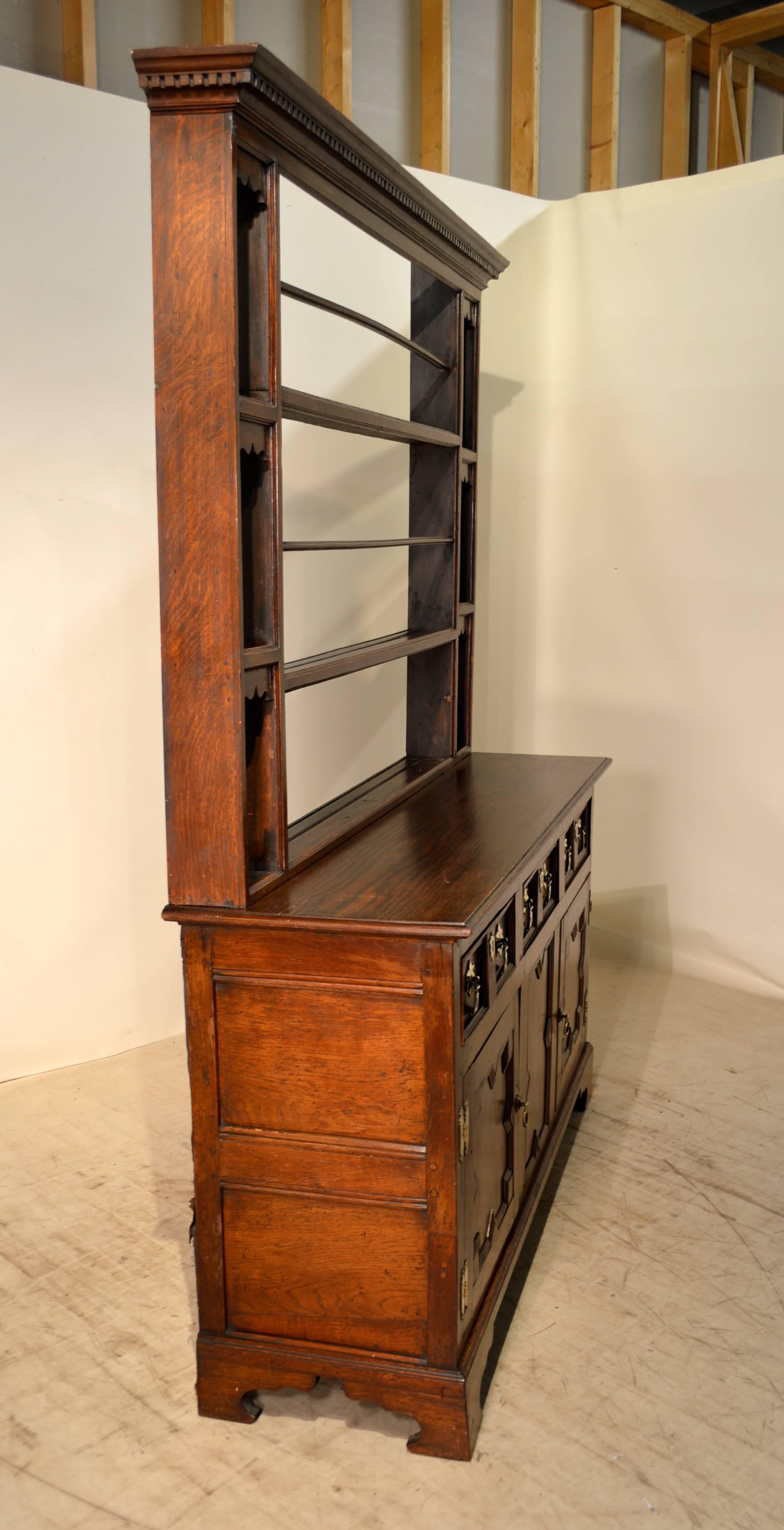 18th century, English oak pewter cupboard with an open-back plate rack. The top has been restored. The base is in good original condition with wear and shrinkage. The sides are paneled. Raised on bracket feet. Serving height, 32.38