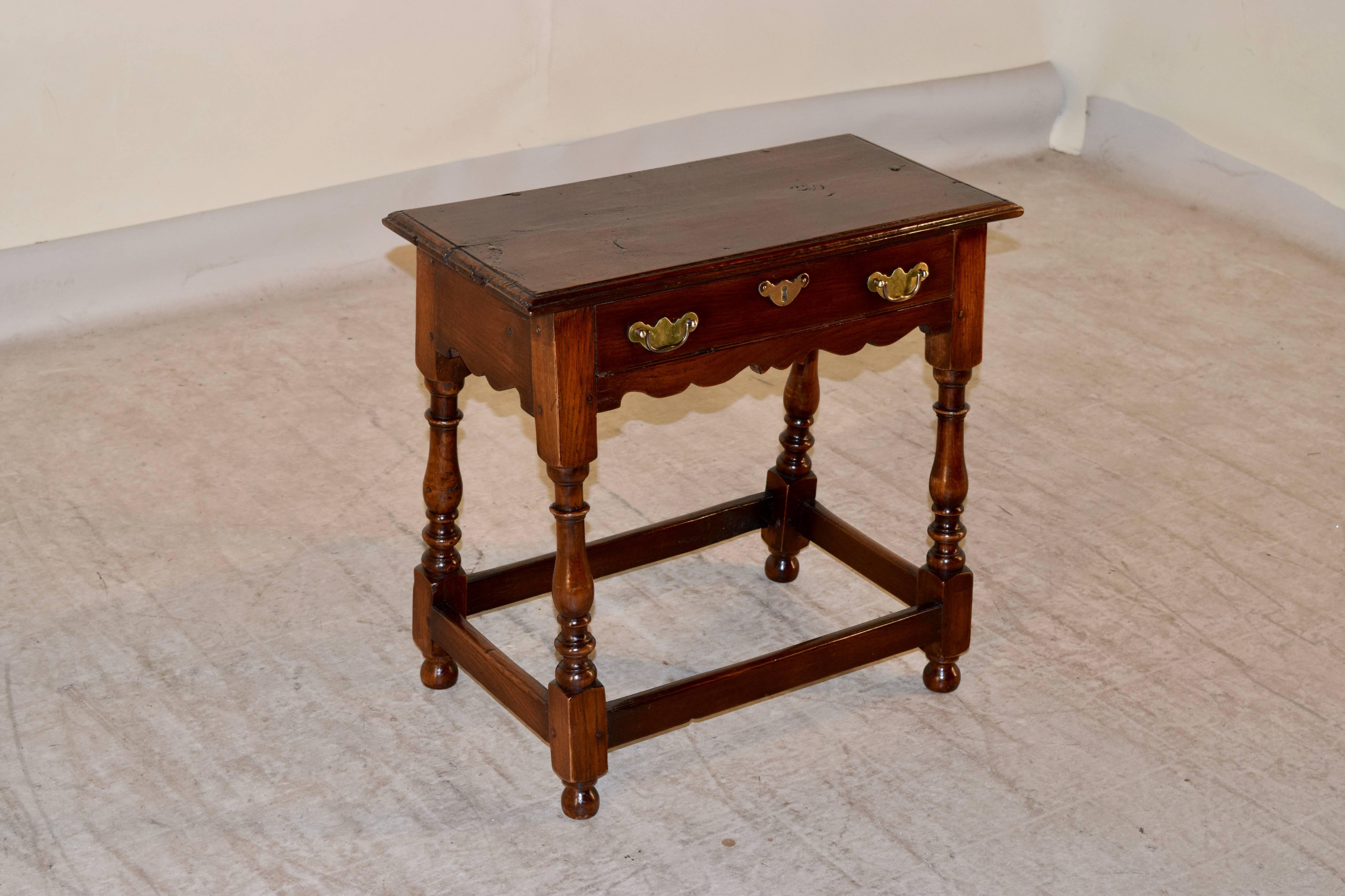 19th Century English oak side table with a two plank top which has a beveled and molded edge and pegged construction. The apron is simple and contains a single drawer in the front. The piece is supported on hand-turned legs, joined by simple