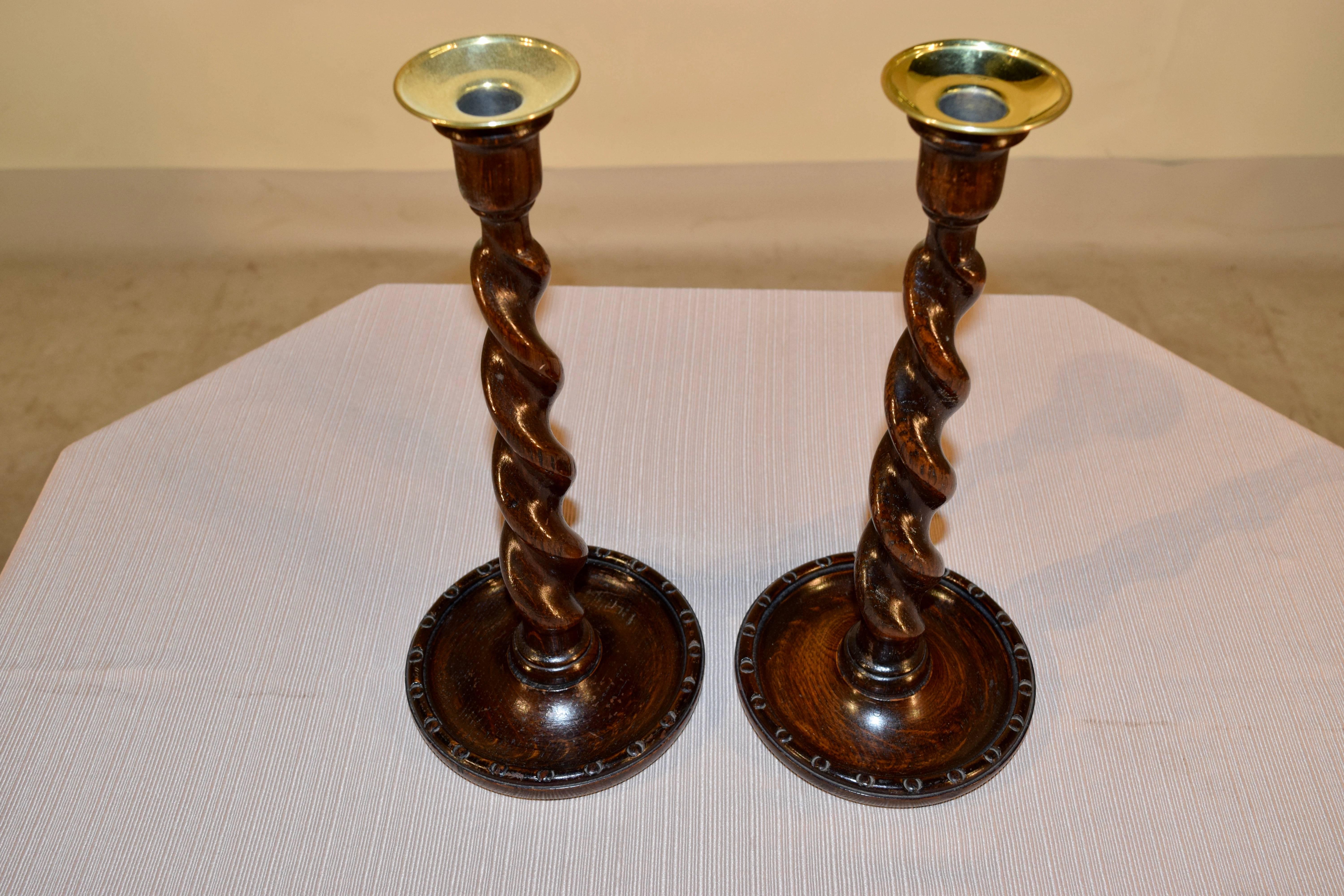 Late 19th century, pair of English oak candlesticks with hand-turned brass bobeches, and hand-turned barley twist stems supported on hand-turned dish shaped bases.