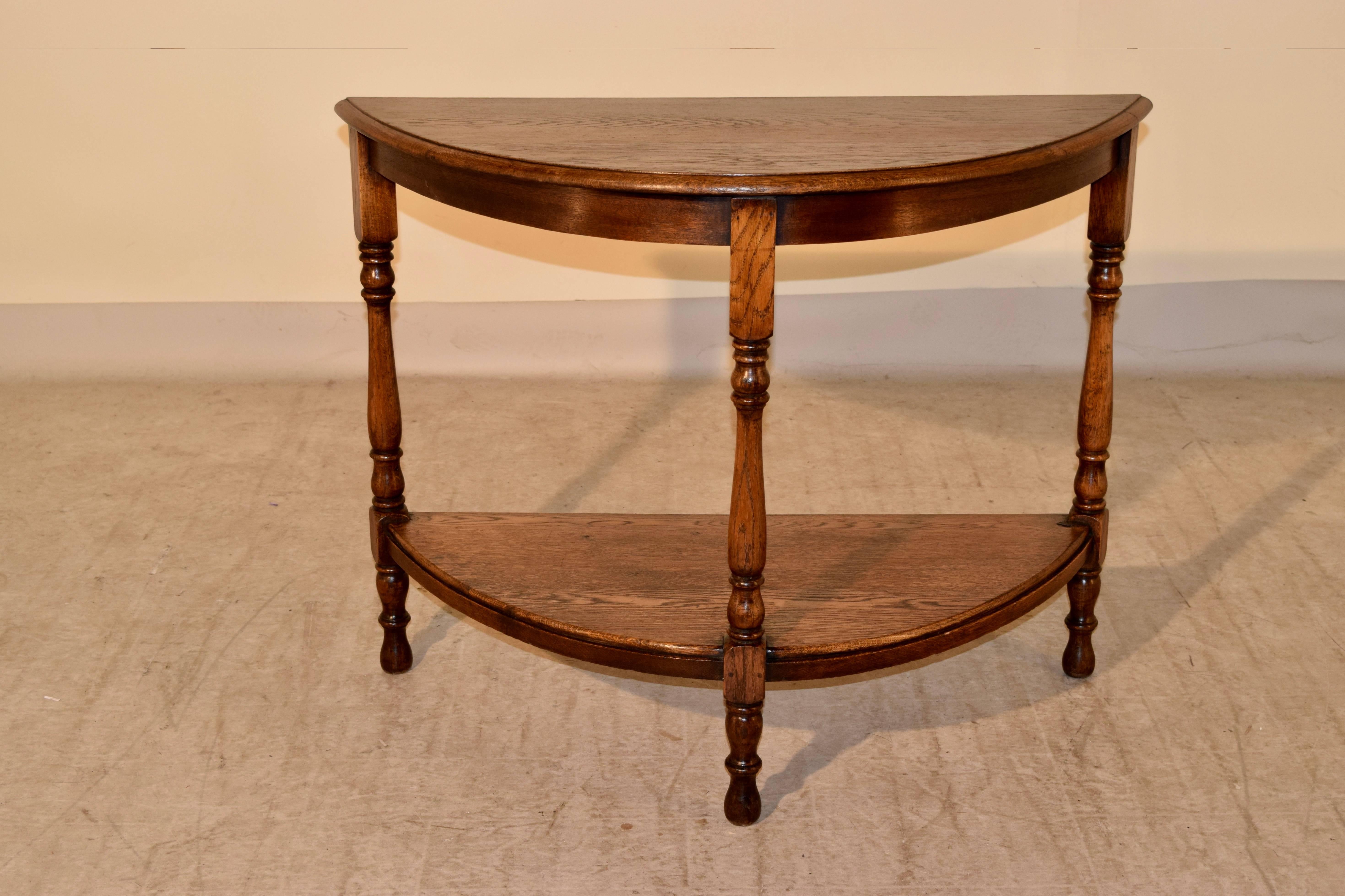 19th century English oak demilune table with a beveled edge around the top following down to a simple apron and hand-turned legs, which are joined at the bottom by a lower shelf, which also has a beveled edge. Supported on hand-turned feet.