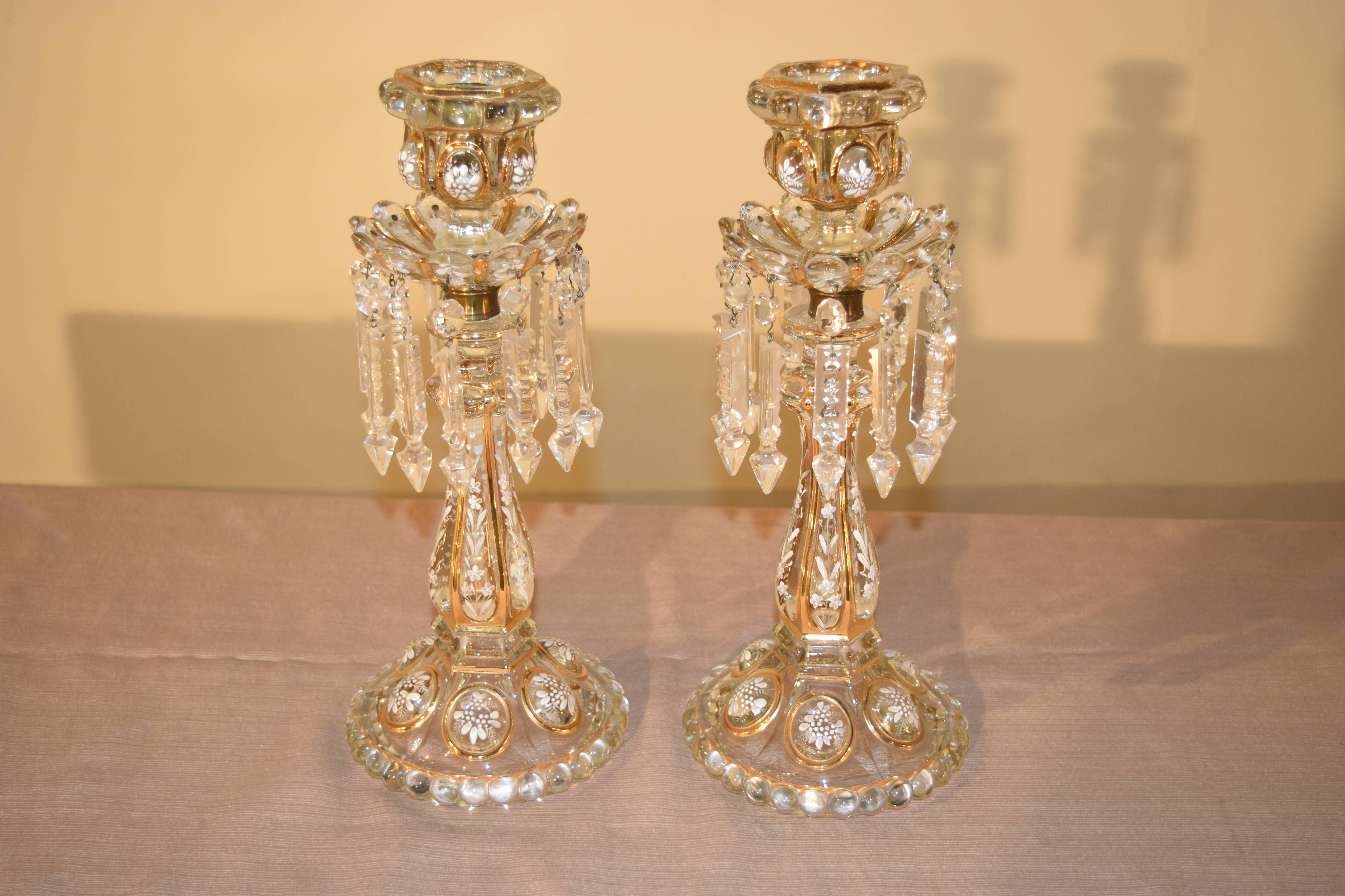 Pair of exquisite Baccarat candlesticks with enameled floral decoration and gilt highlights, circa 1900. They have cut-glass prisms as well.