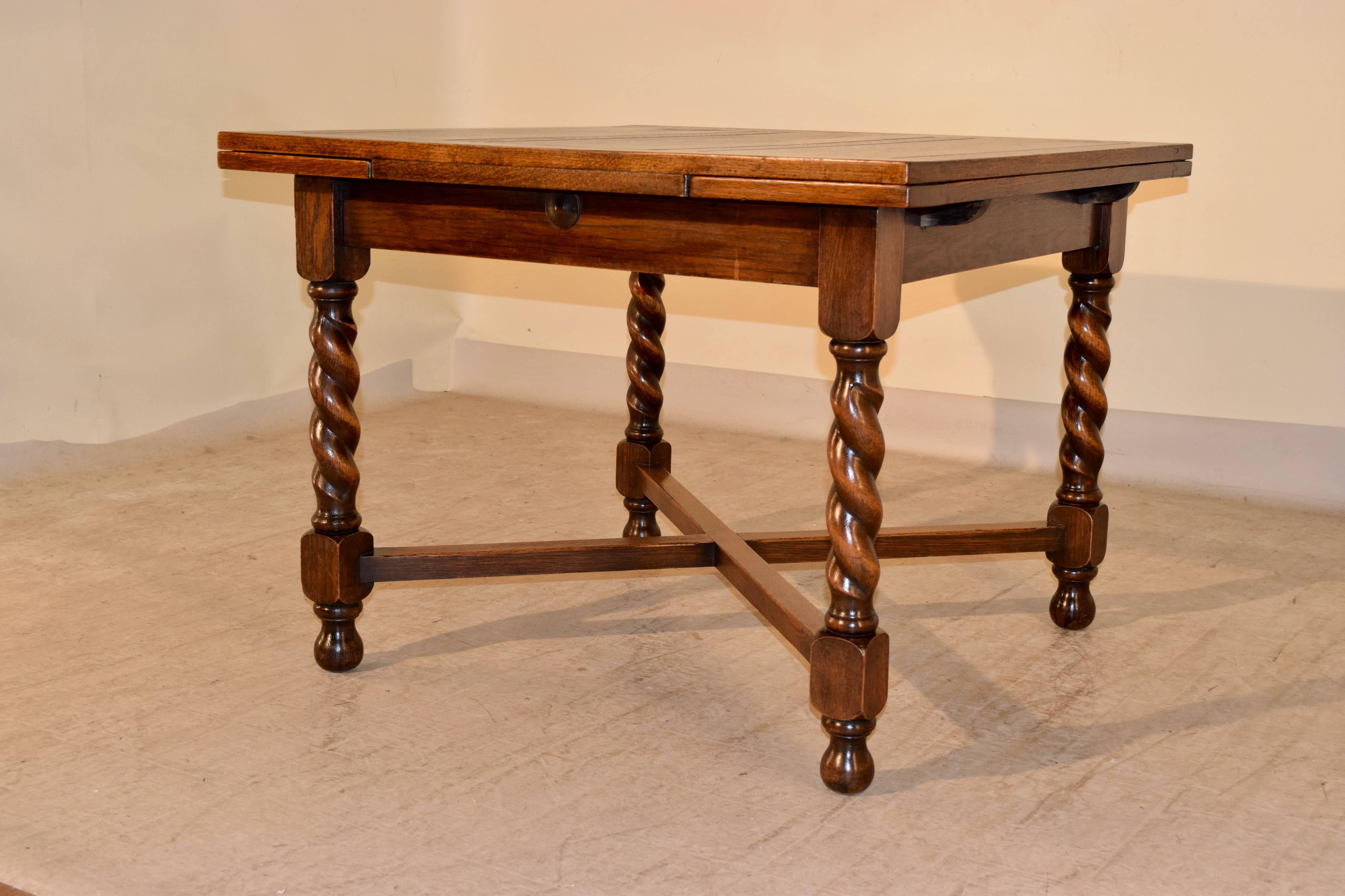Late 19th century English oak table with two draw leaves. The top and leaves are paneled and follow down to a simple apron. The piece is supported on hand-turned barley twist legs, joined by cross stretchers and raised on turned feet. Top open