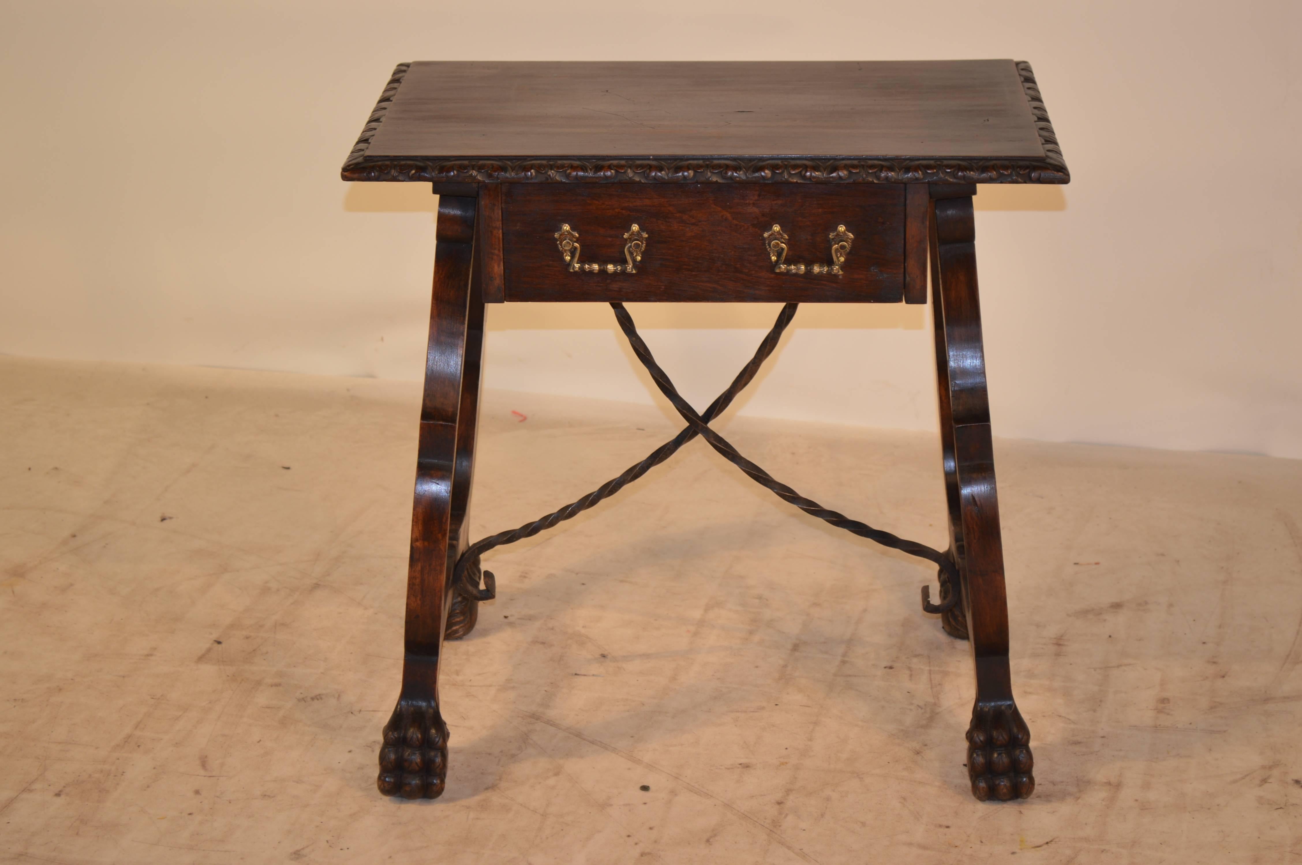 Italian walnut side table with a carved and beveled edge around the top, following down to a single drawer, flanked by Italian vase shaped legs with carved paw feet and hand-wrought iron supports. circa 1900.