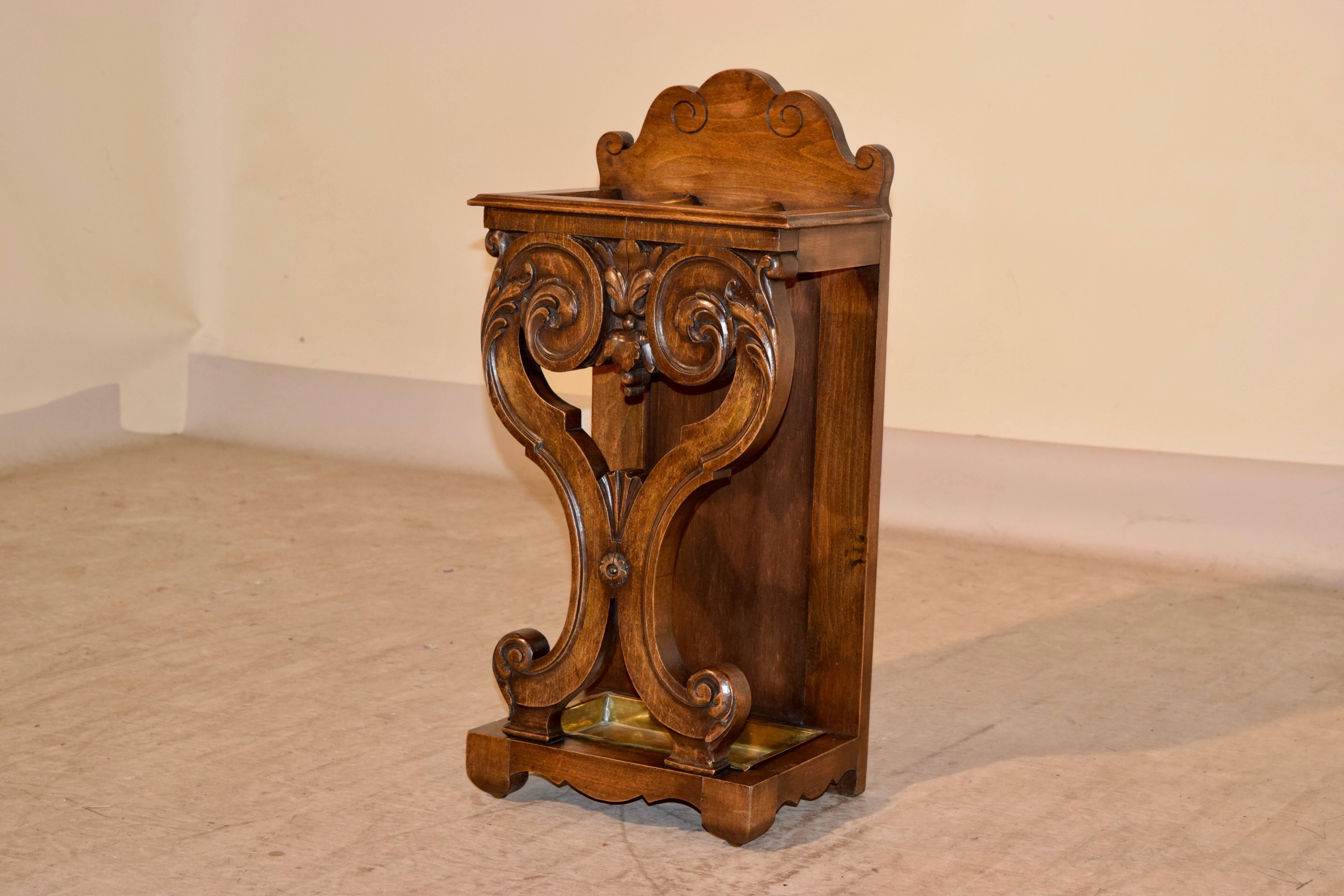 Late 19th century umbrella stand from England. The back is scalloped and has lovely decoration which enhances the gorgeous carving on the front. The base has a scalloped skirt and the original brass drip tray.