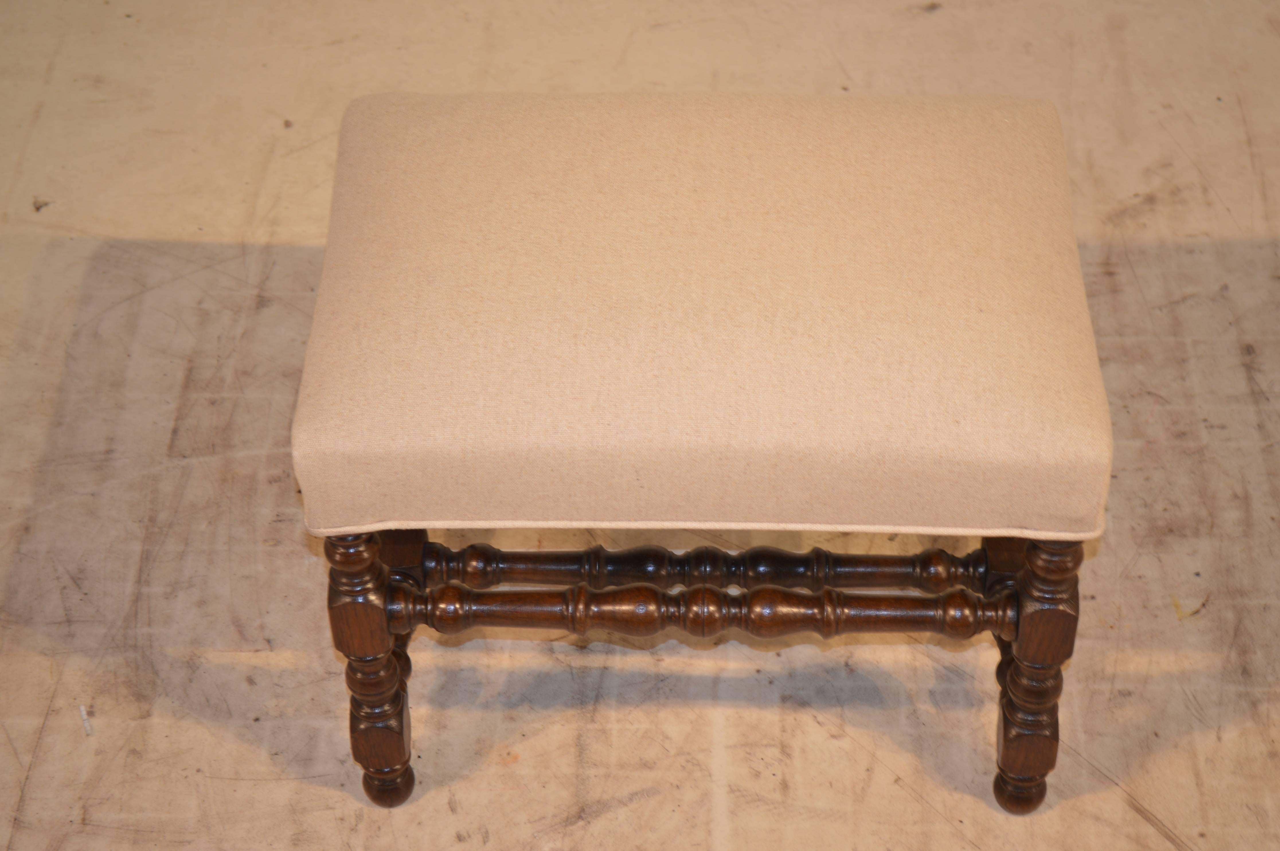 19th century English oak bench with nicely turned legs and stretchers. Raised on turned feet. Newly upholstered in linen with a single welt decoration.