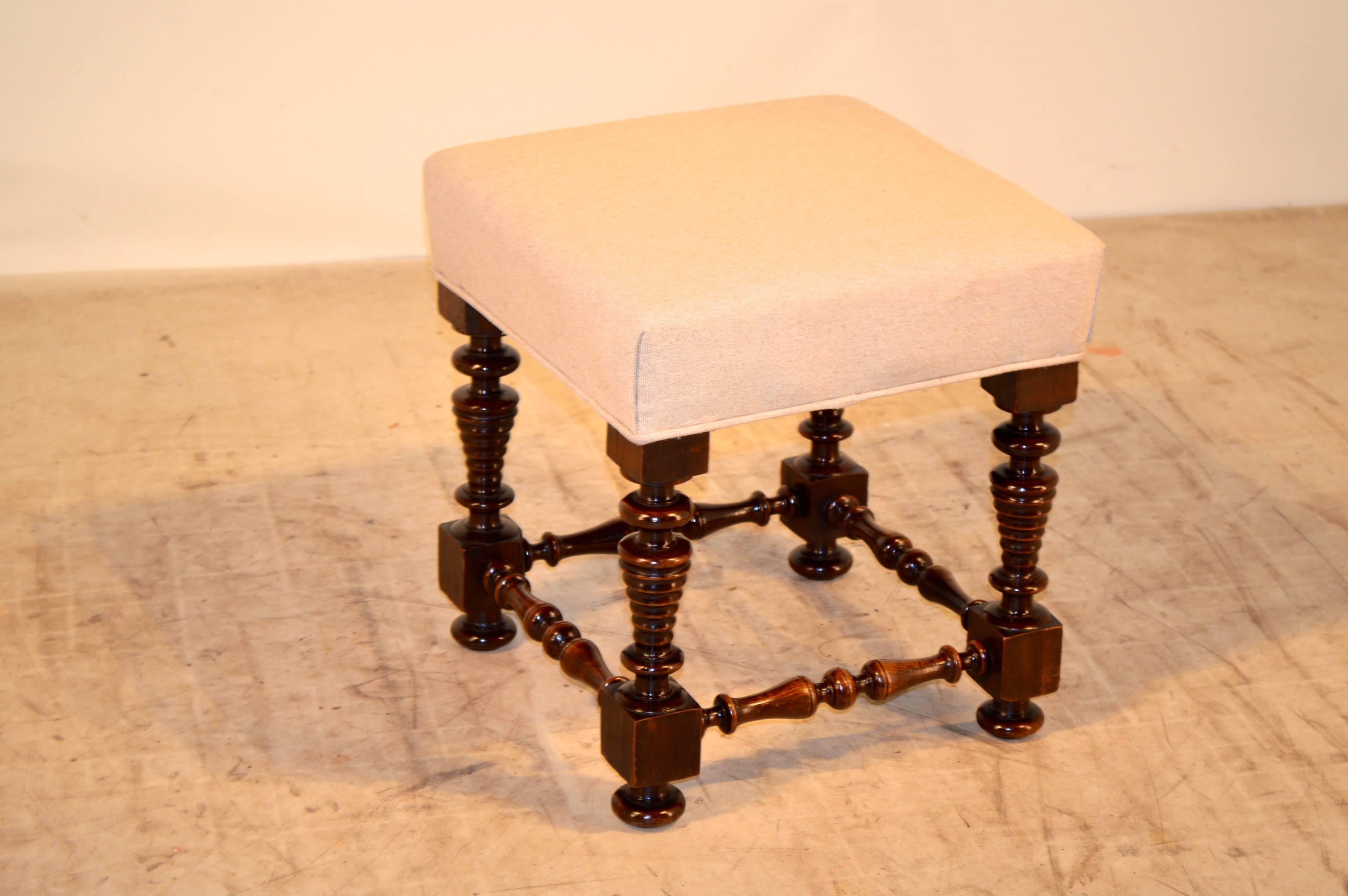 19th century English mahogany stool with a newly upholstered top in linen. The legs are exquisitely hand-turned in a beehive shape, joined by turned stretchers. Raised on turned feet.